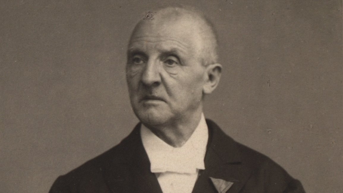 Portrait of Anton Bruckner. He is looking to his right side, holding documents in his hands.