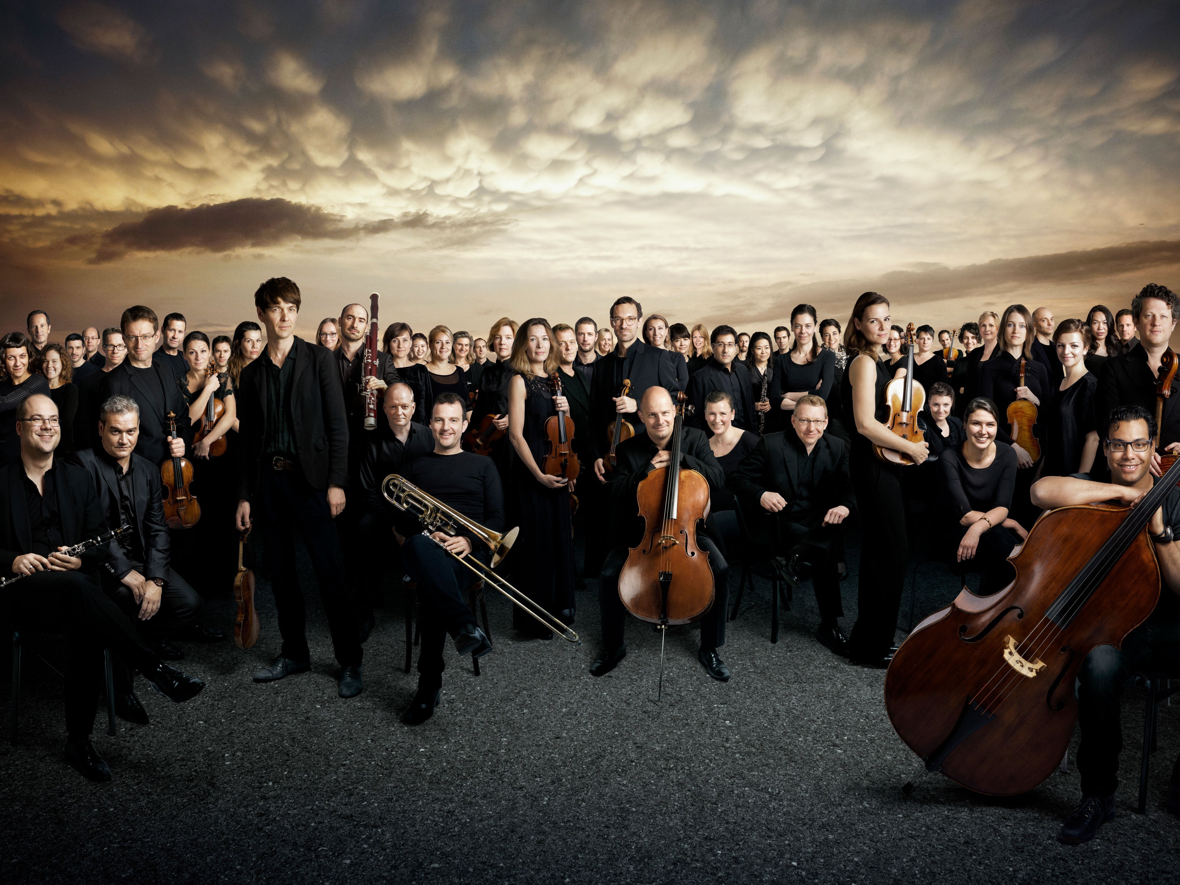 Gruppenbild des Orchesters vor dramatischem Himmel