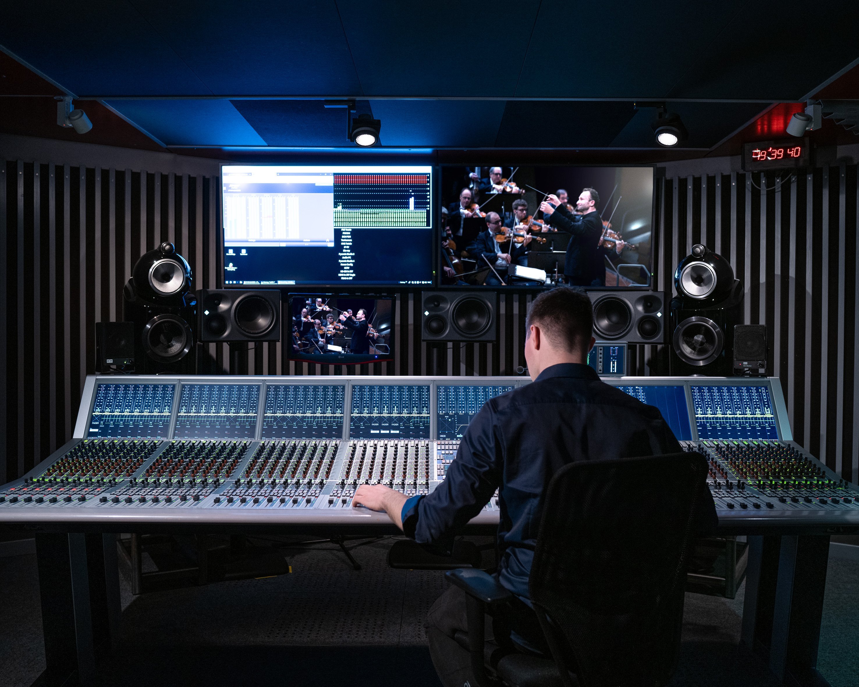 A tonmeister is sitting in front of a mixing desk.