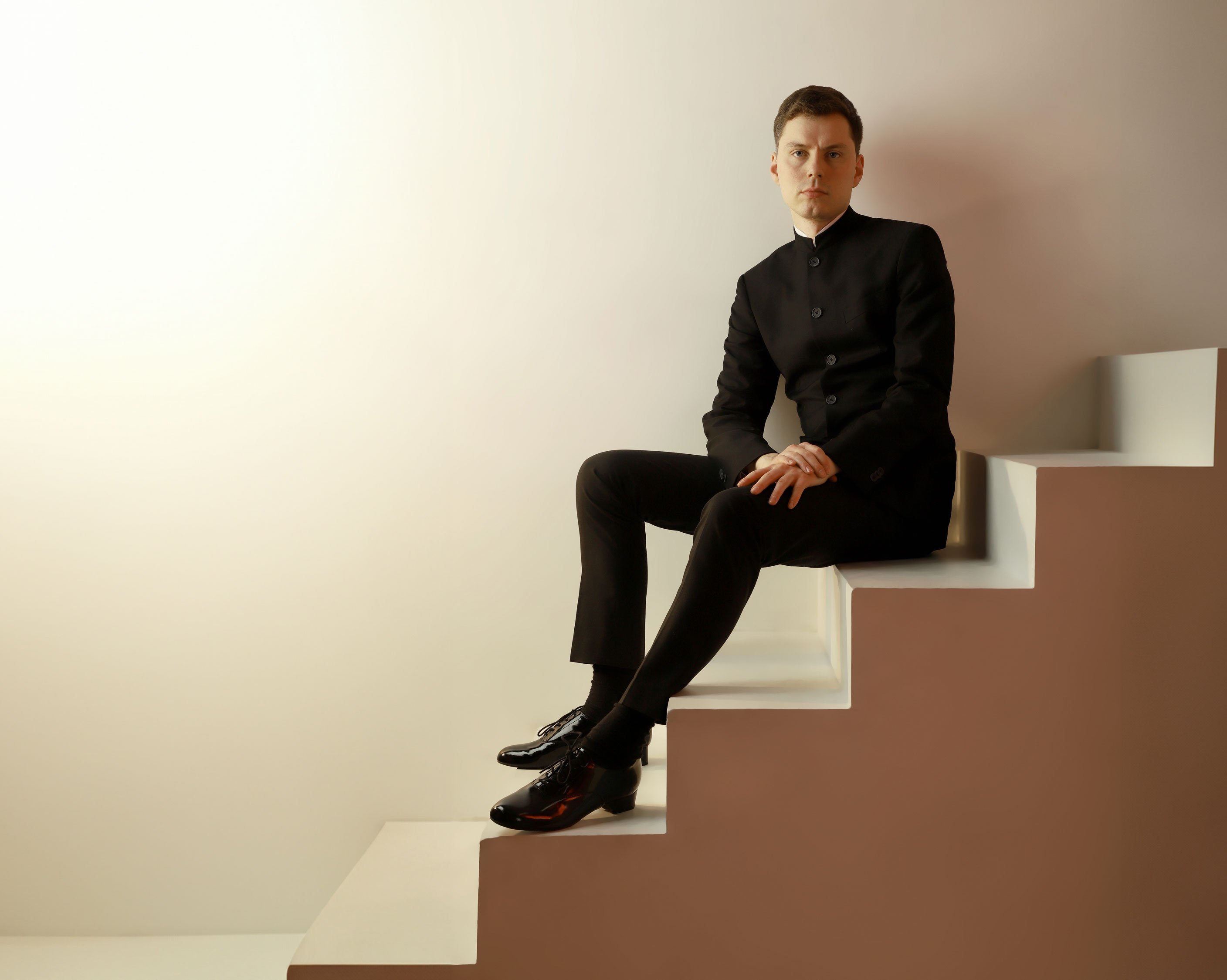 Richard Gowers sits on a staircase in a suit