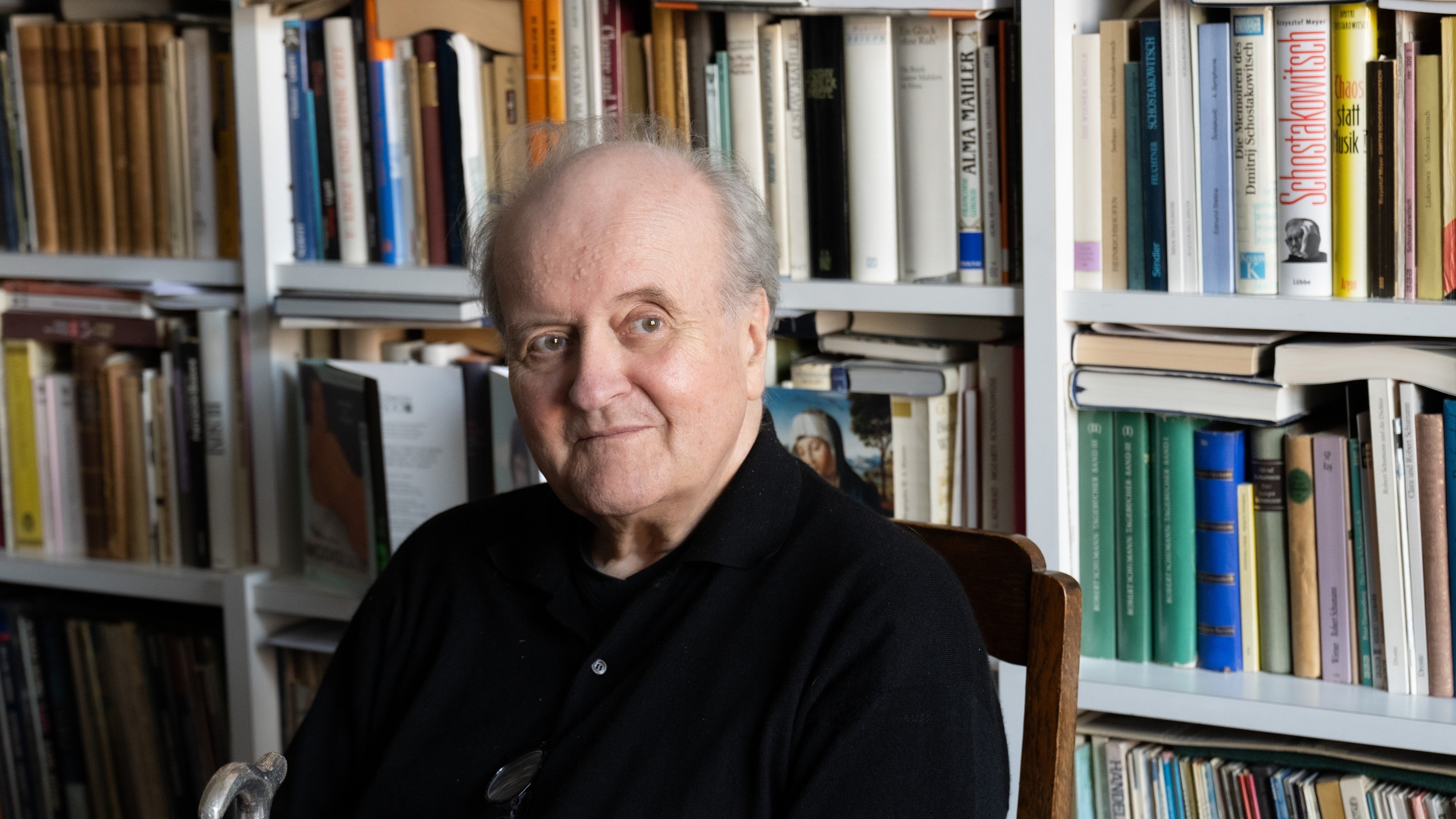 Wolfgang Rihm sitzt zuhause vor seinem Bücherregal