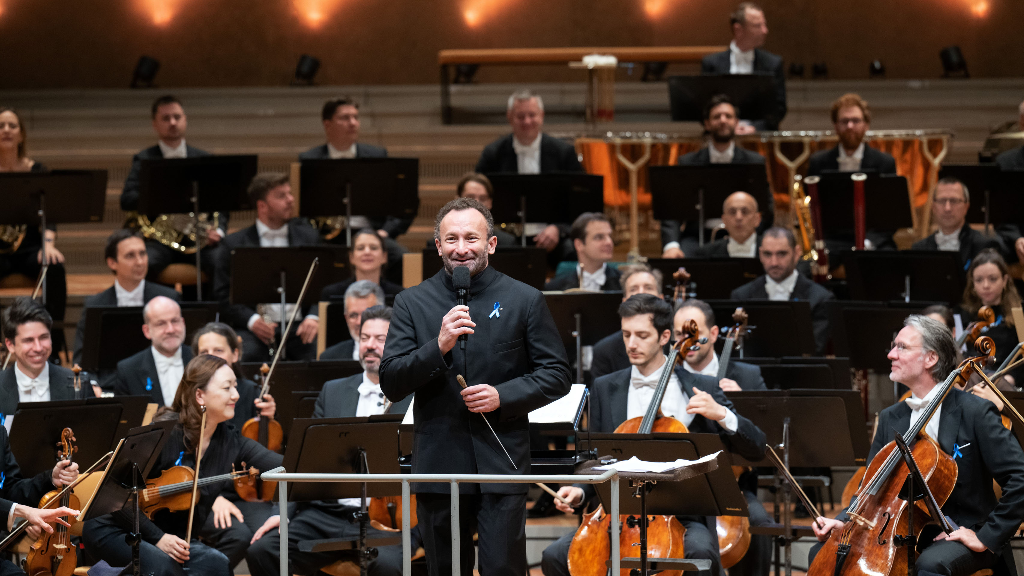 Kirill Petrenko with microphone in front of the orchestra