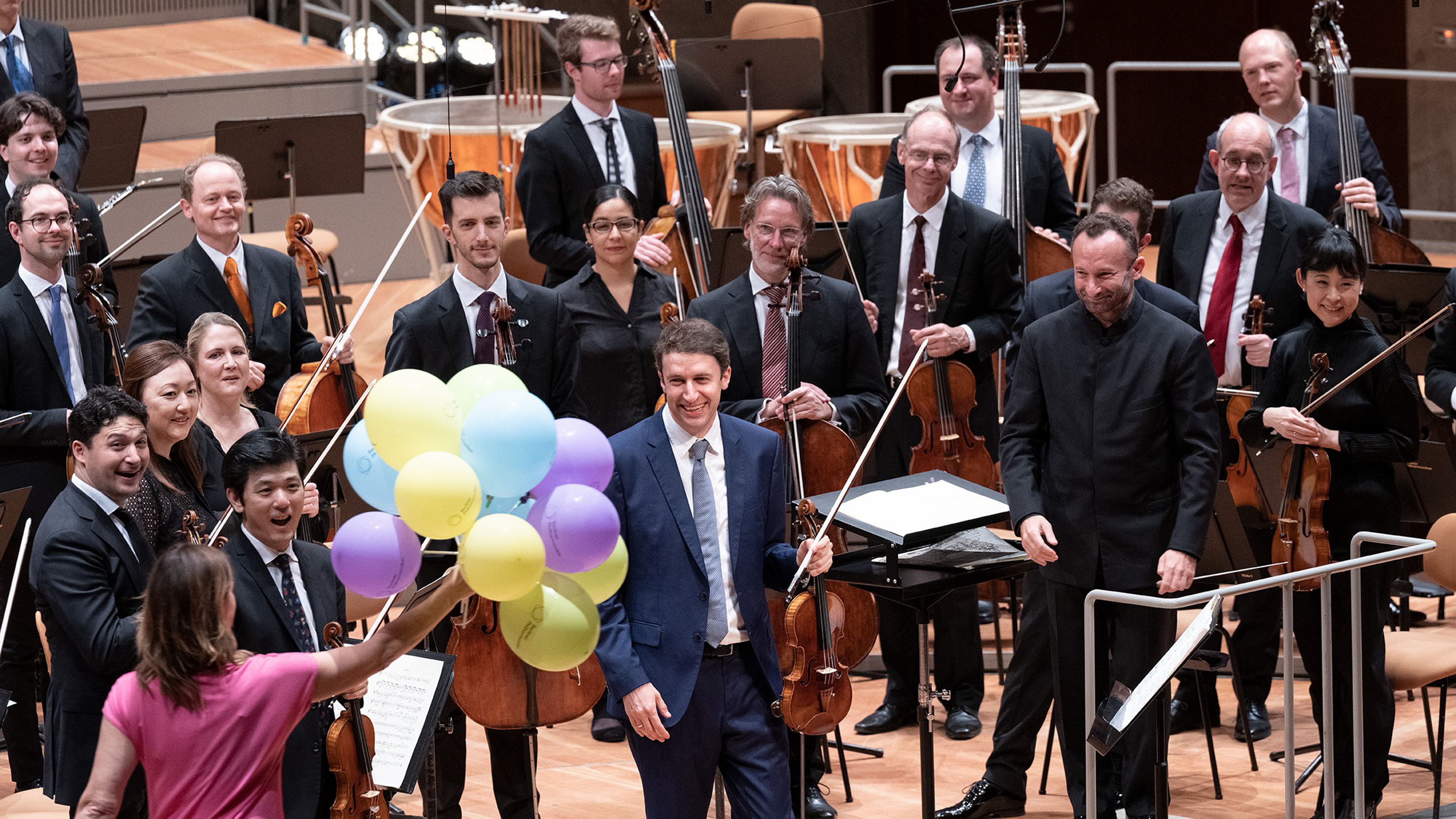 Woman with lots of colourful balloons joins the musicians on stage