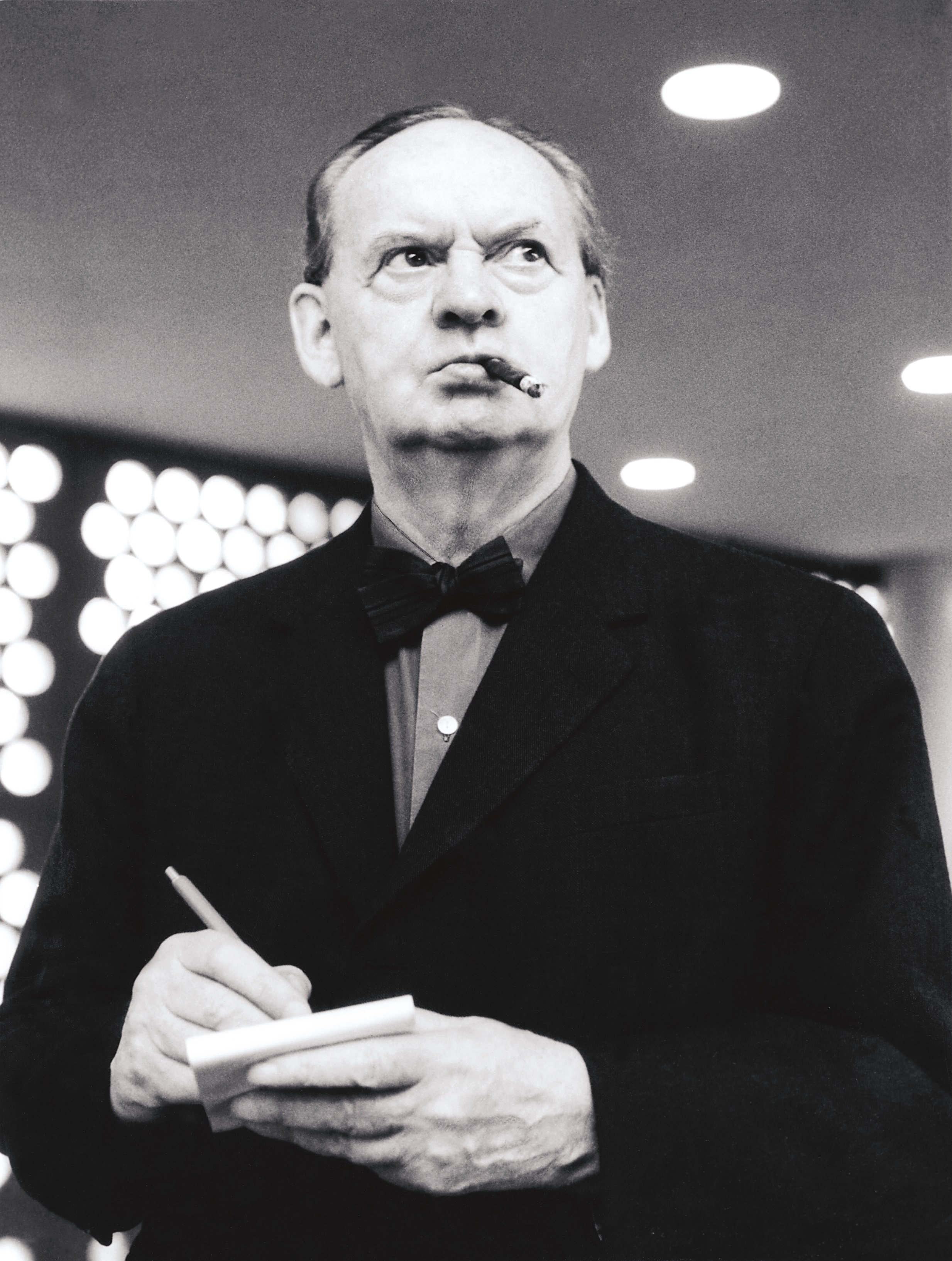 Hans Scharoun with a cigarette in his mouth and a note pad and pencil in his hands.