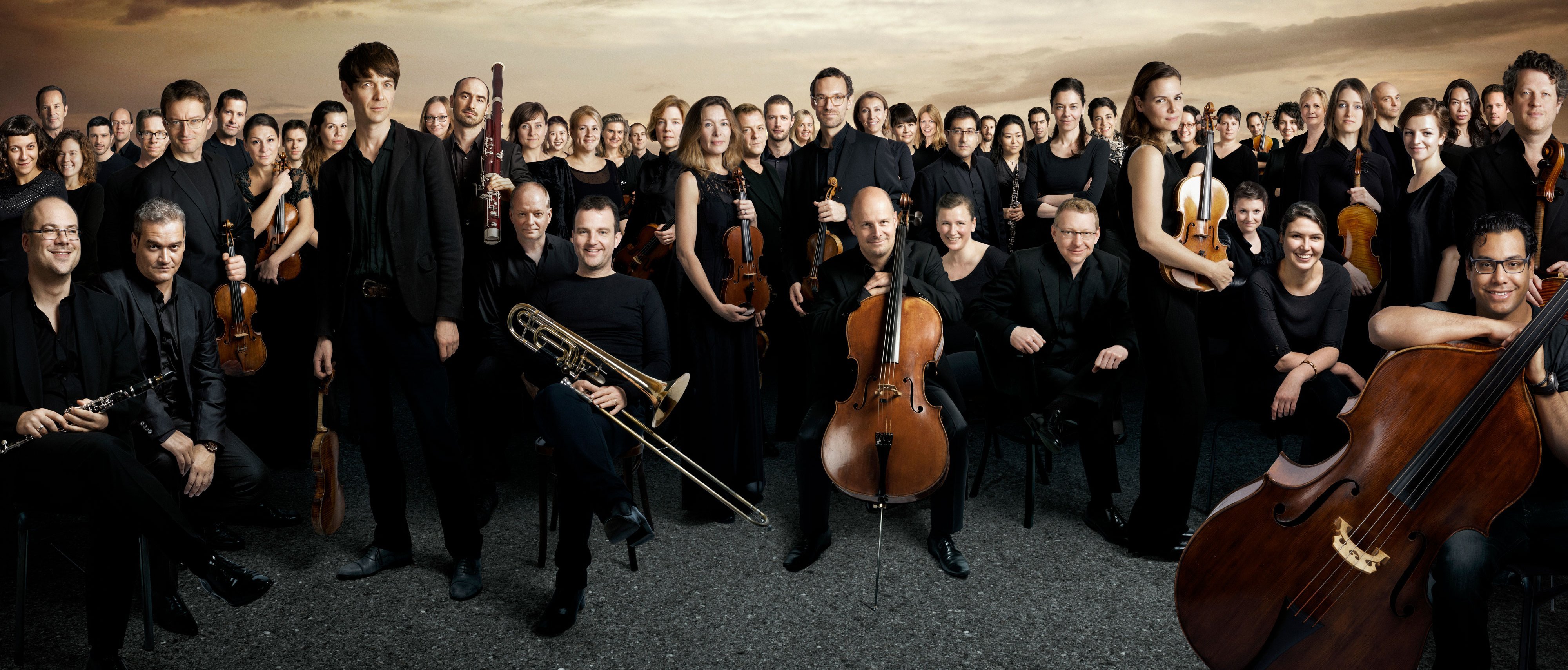 Gruppenbild des Orchesters vor dramatischem Himmel