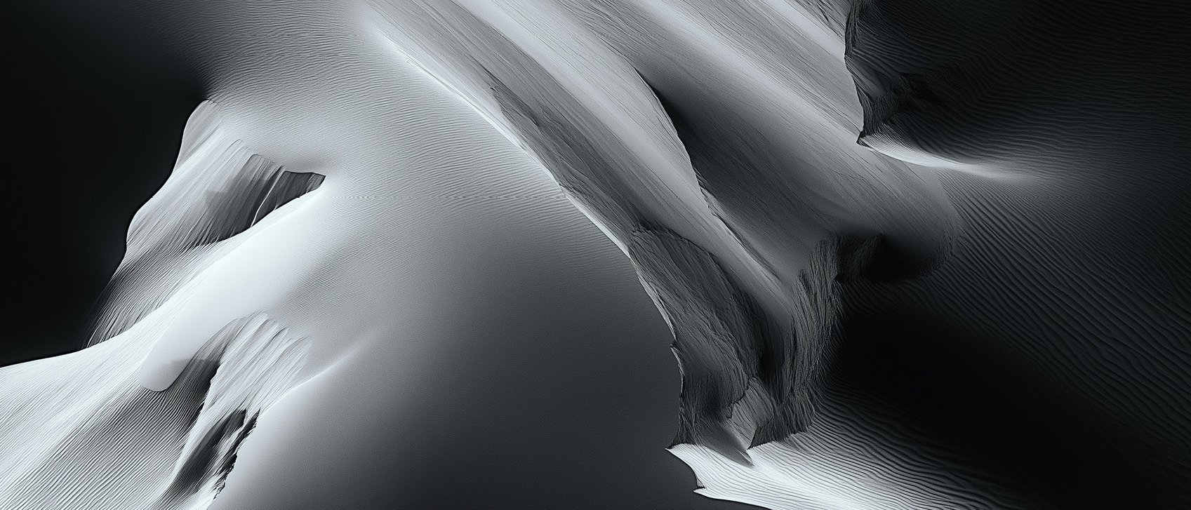 Abstrakte Luftaufnahme von glatten, fließenden Sanddünen oder Bergkämmen mit dramatischen Lichtern und Schatten, die ein monochromes, strukturiertes Landschaftsmuster in Schwarz-, Weiß- und Grautönen erzeugen.