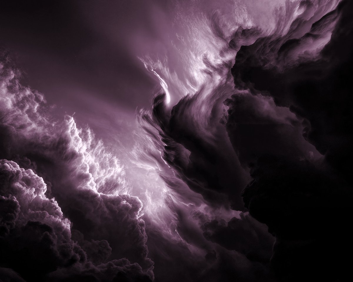 Lila gefärbte Wolken wirbeln dramatisch am Himmel, und helles Licht beleuchtet Teile der dichten, stürmischen Formationen und schafft eine ätherische und intensive Atmosphäre.