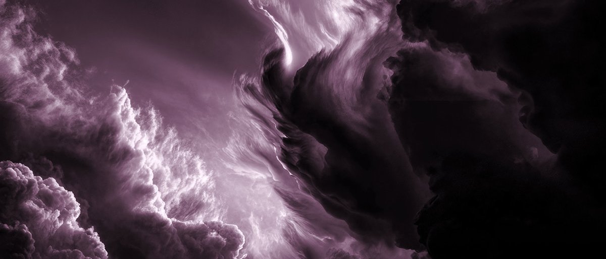 Lila gefärbte Wolken wirbeln dramatisch am Himmel, und helles Licht beleuchtet Teile der dichten, stürmischen Formationen und schafft eine ätherische und intensive Atmosphäre.