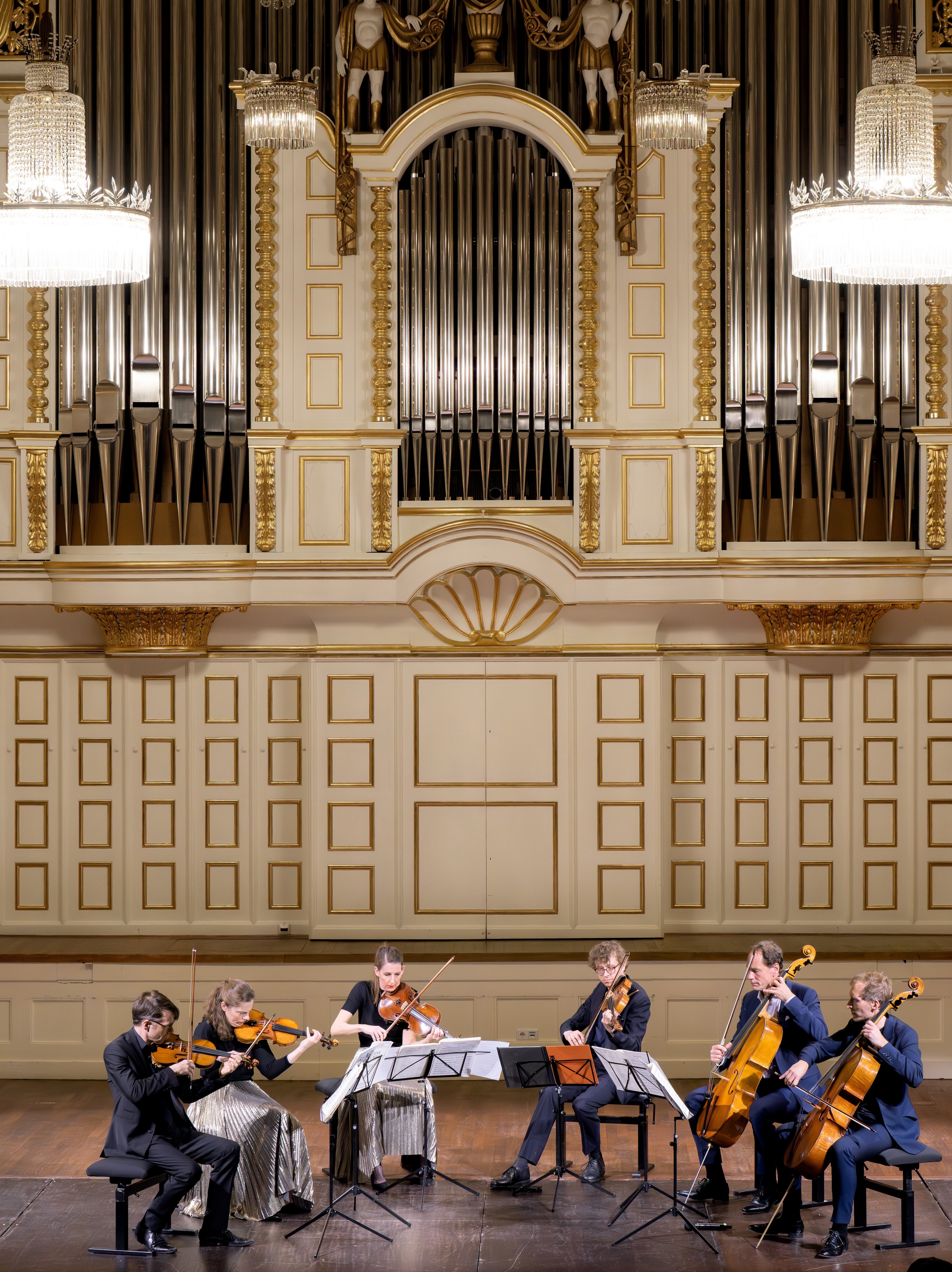 Ein Streichsextett spielt auf einer Bühne, im Hintergrund ist eine große Orgel zu sehen.