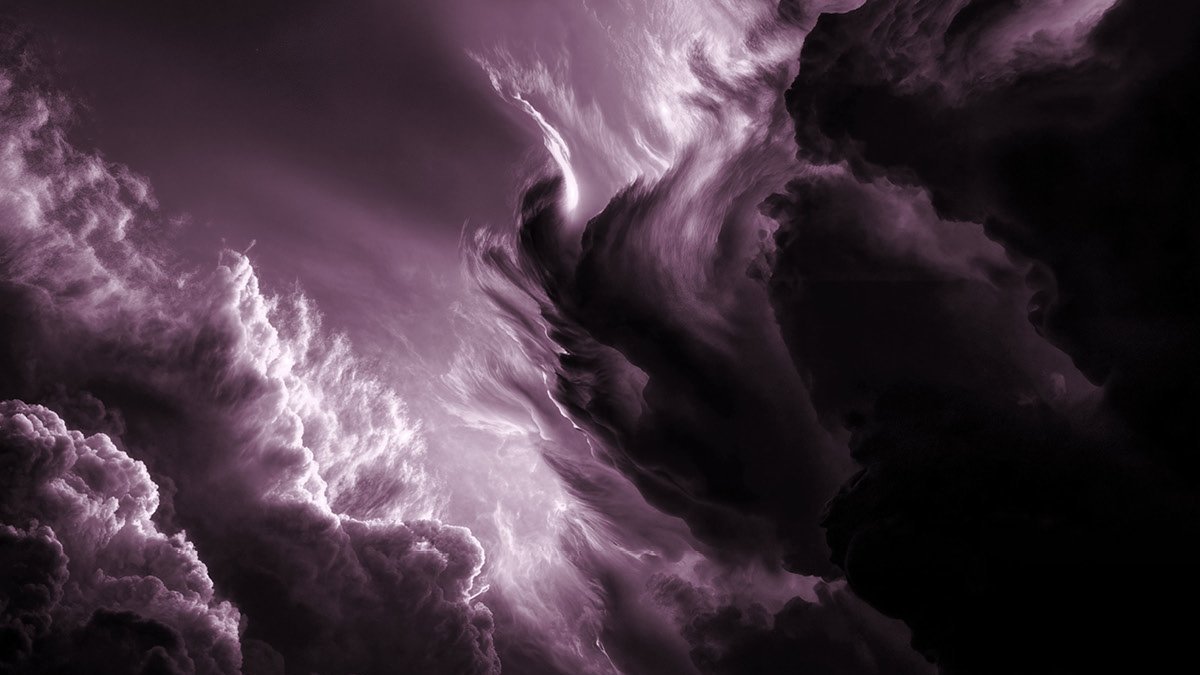 Dramatic, swirling clouds illuminated in shades of deep purple and white, creating a mysterious and intense atmosphere in the sky.