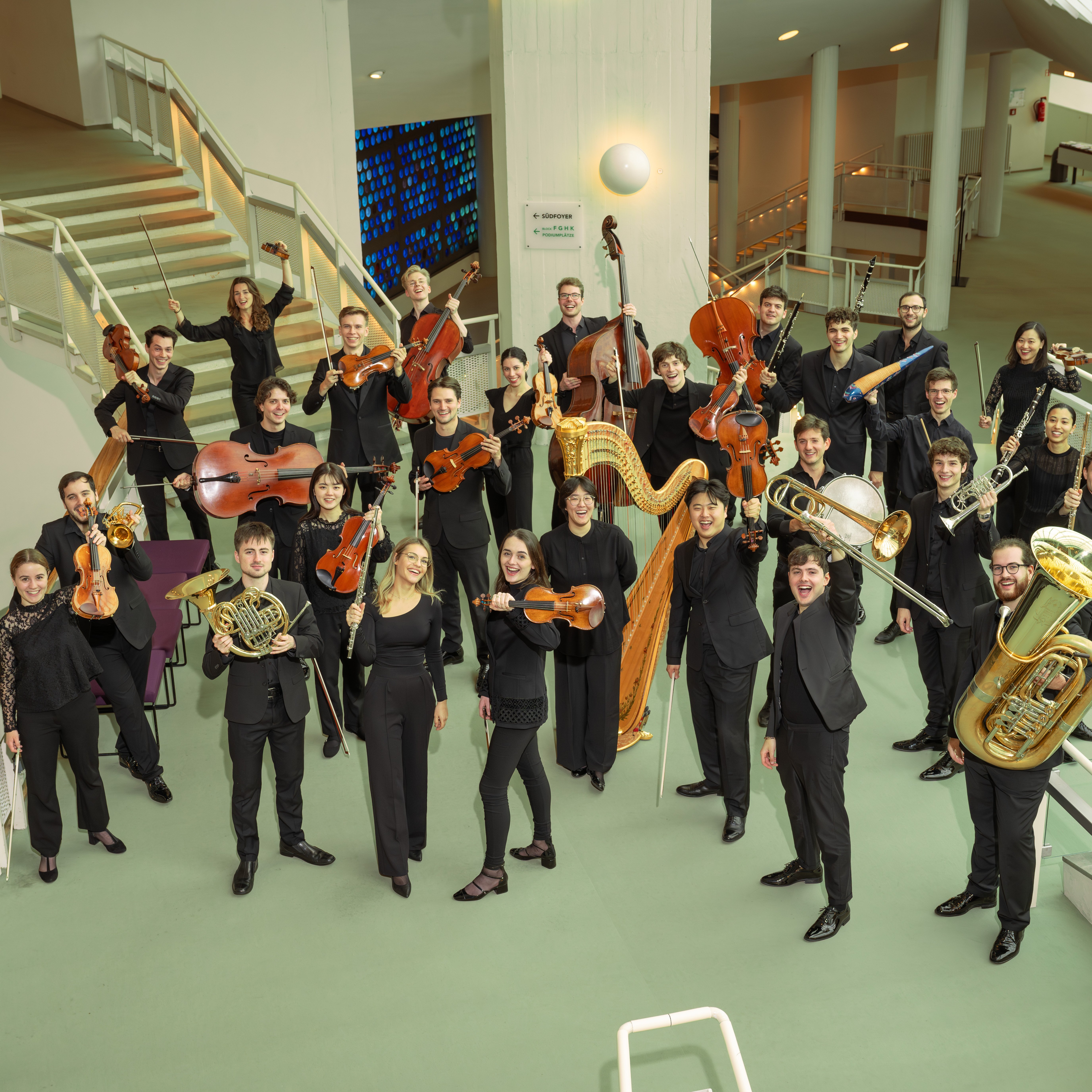 Gruppenbild mit Musiker:innen mit ihren Instrumenten im Foyer der Philharmonie Berlin