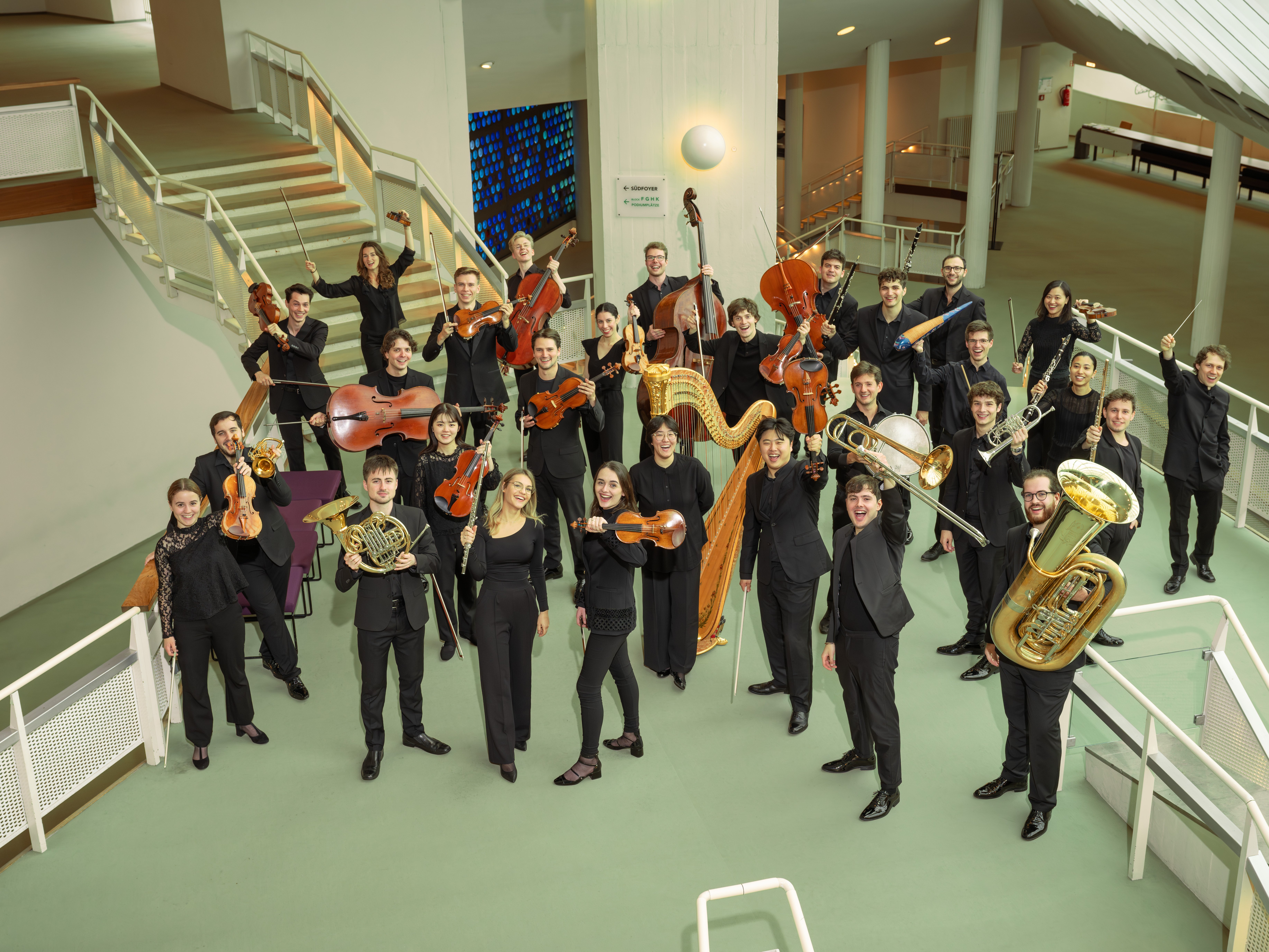 Gruppenbild mit Musiker:innen mit ihren Instrumenten im Foyer der Philharmonie Berlin