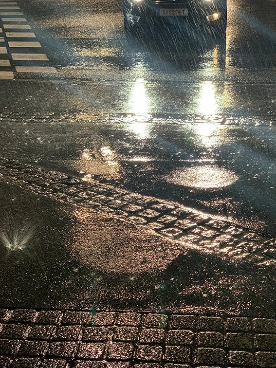 Wet street, mirroring lights of a car
