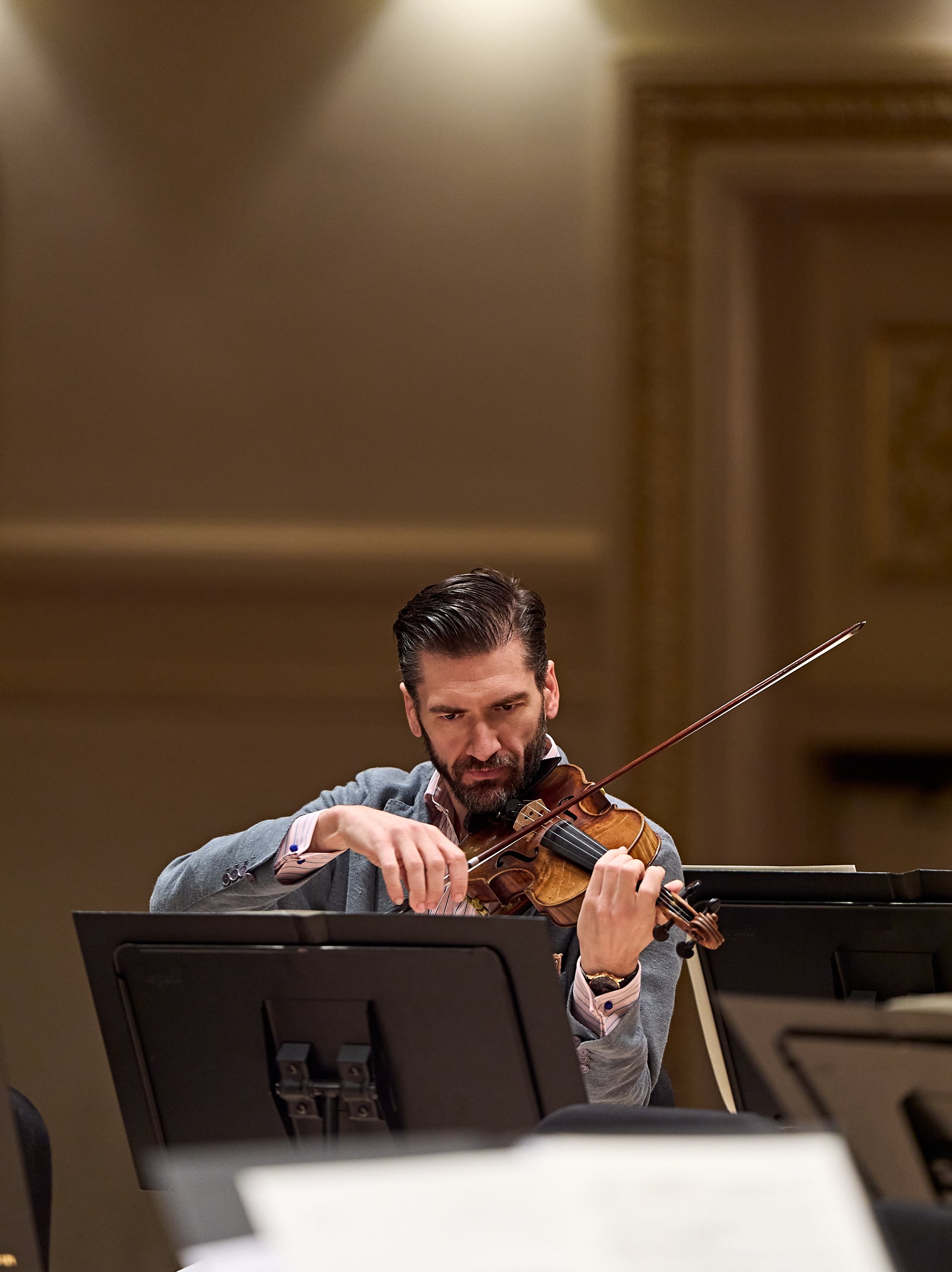 Ein konzentrierter Geiger, der während eines Orchesterkonzerts spielt.