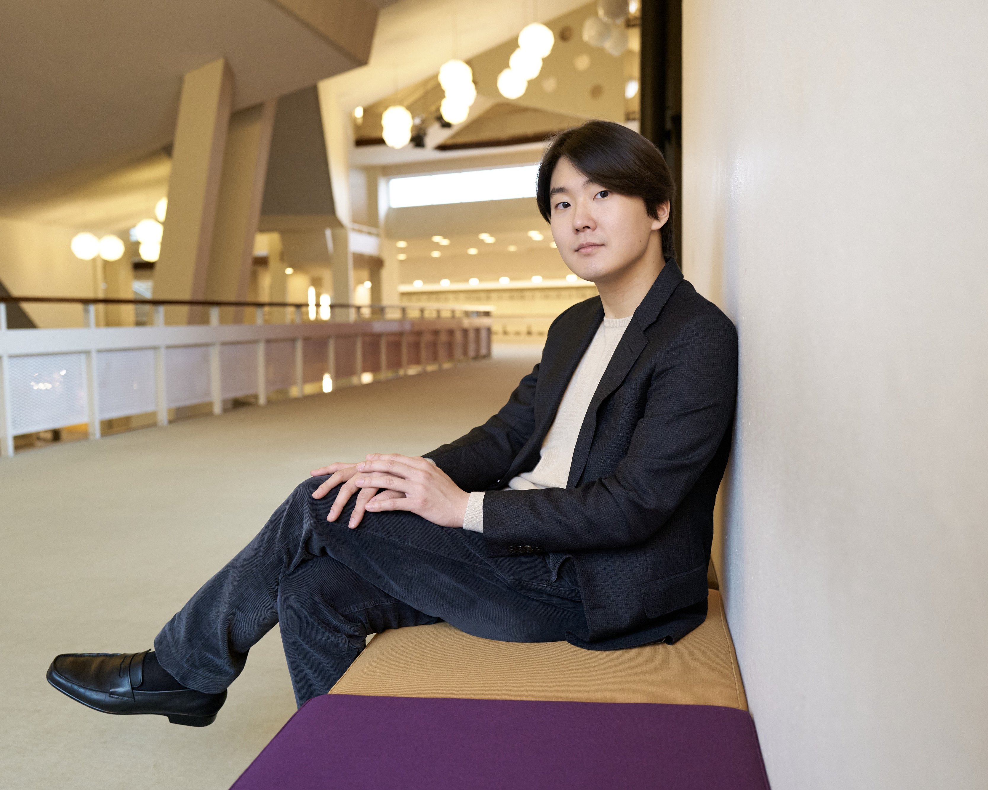 Seong-Jin Cho sitzt auf einer Bank in der Philharmonie Berlin