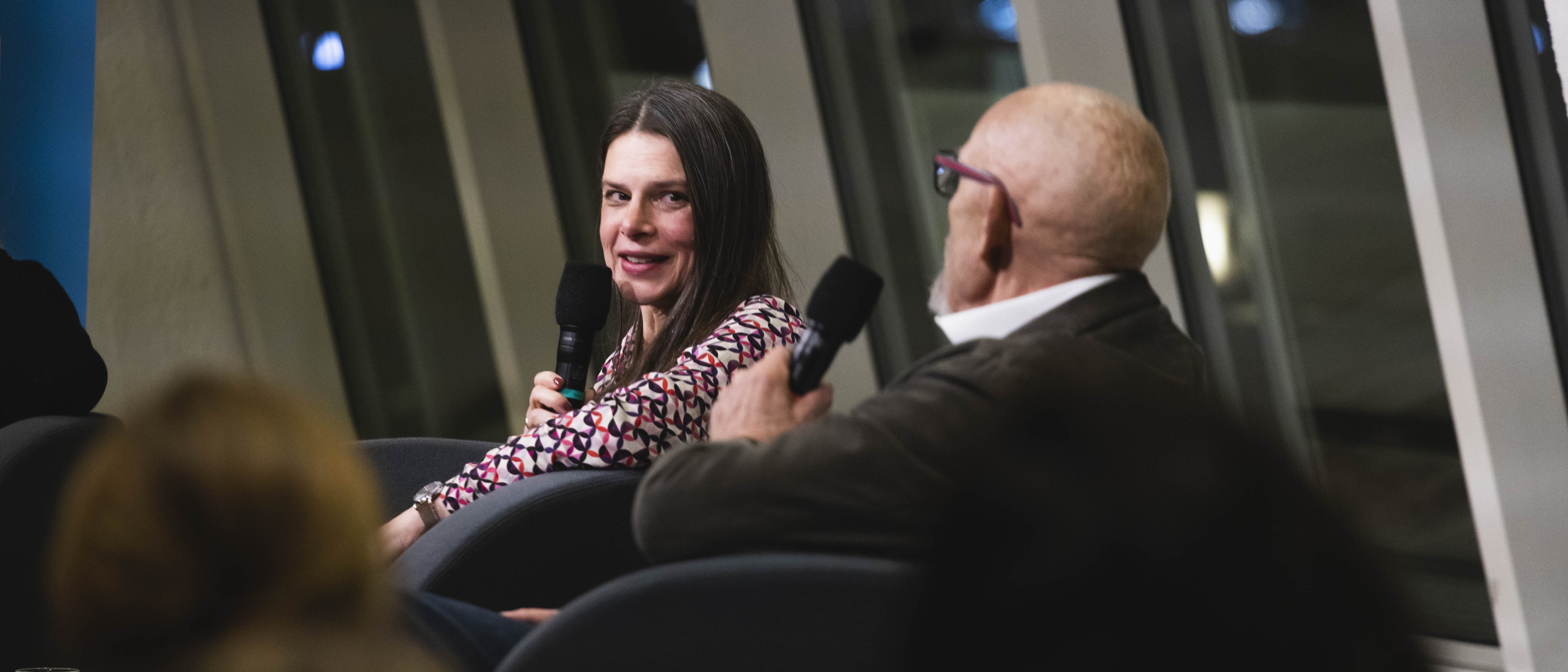 Die Moderatorin Christiane Florin sitzt im Foyer in der Philharmonie Berlin und spricht in ein Mikrofon.