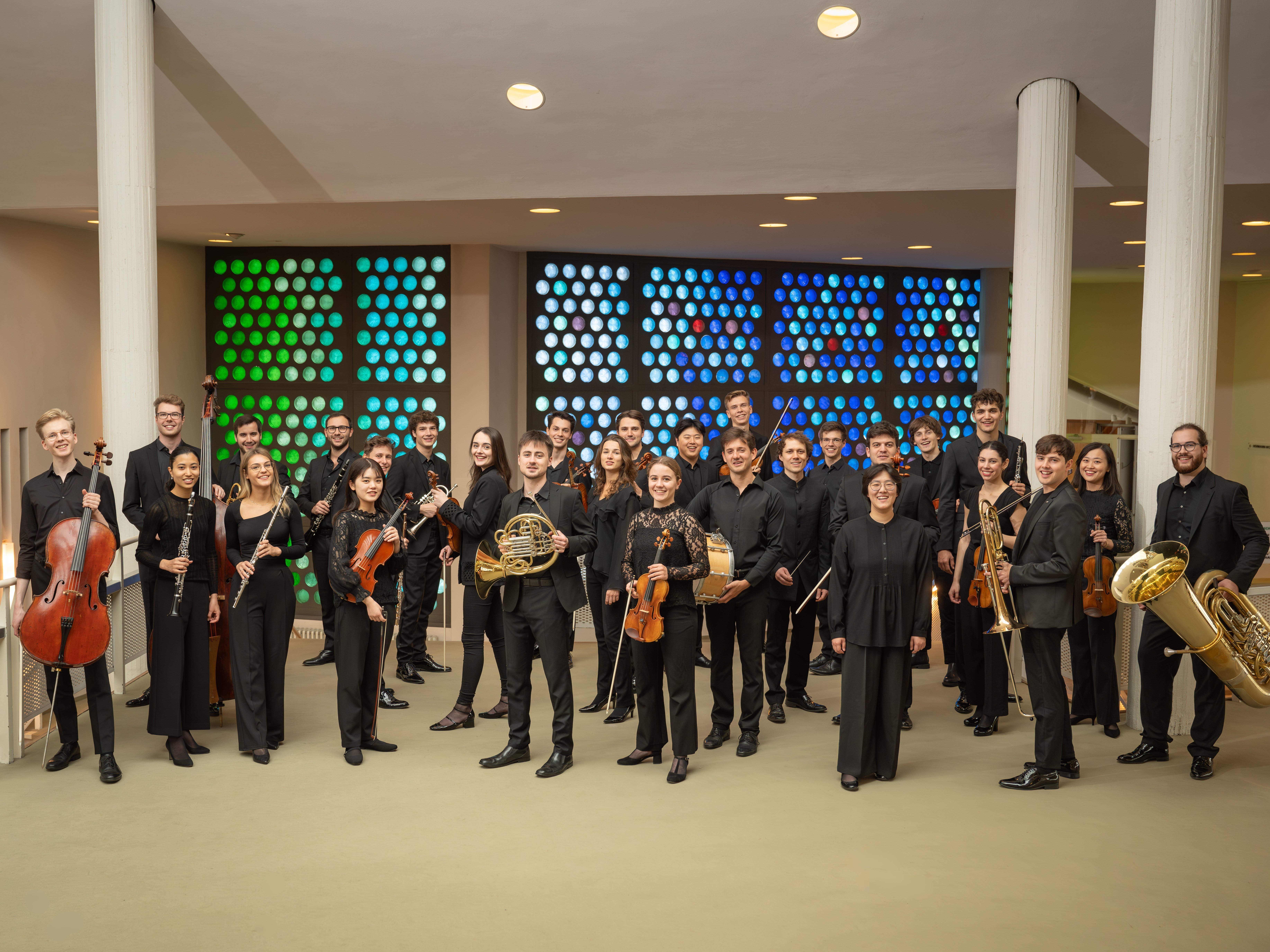 Ein Gruppenfoto der Mitglieder der Karakan-Akademie. Die Musiker*innen stehen mit ihren Instrumentenn und schwarzer Kleidung im Foyer der Philharmonie.