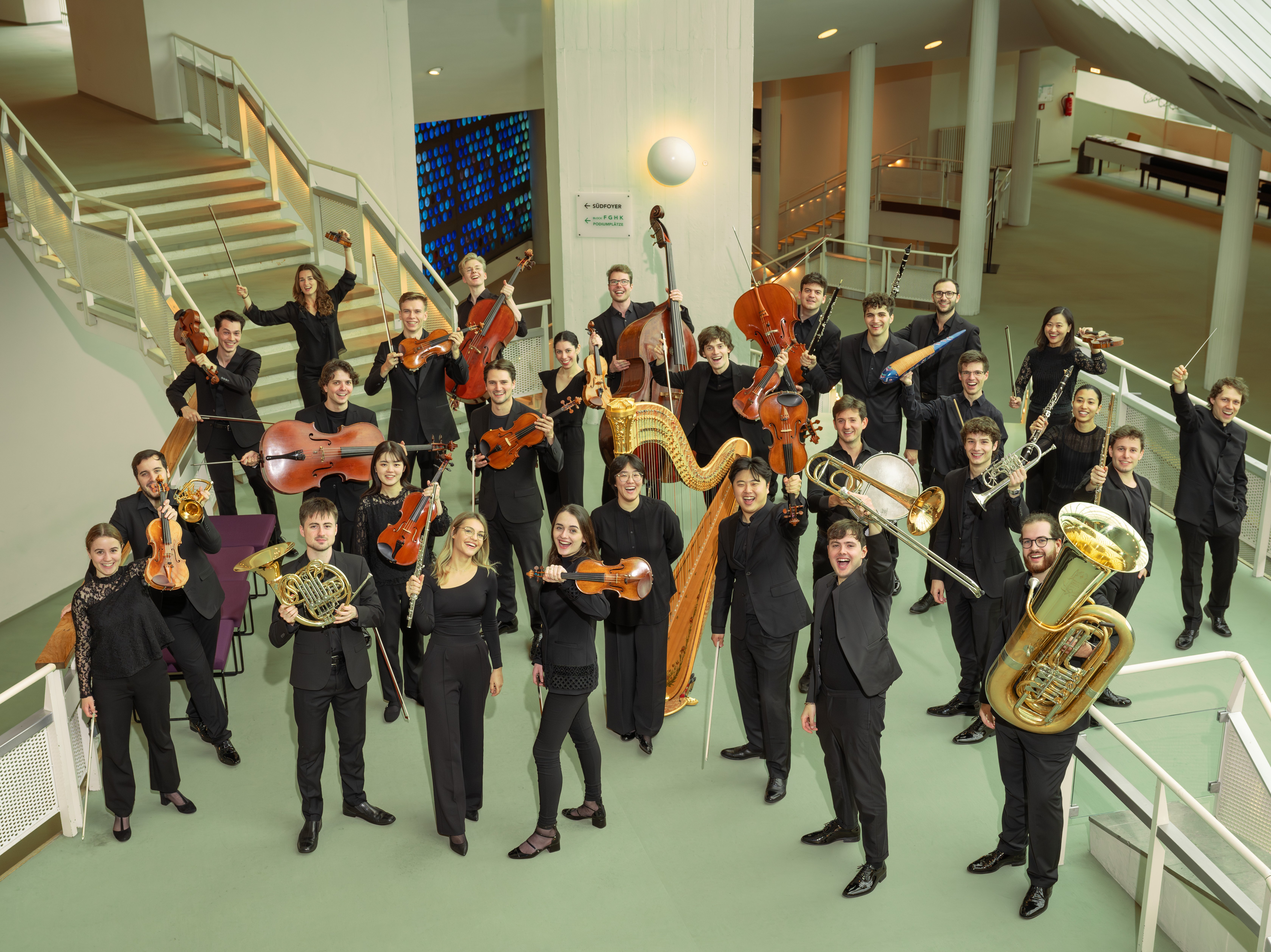 Gruppenbild mit Musiker:innen mit ihren Instrumenten im Foyer der Philharmonie Berlin