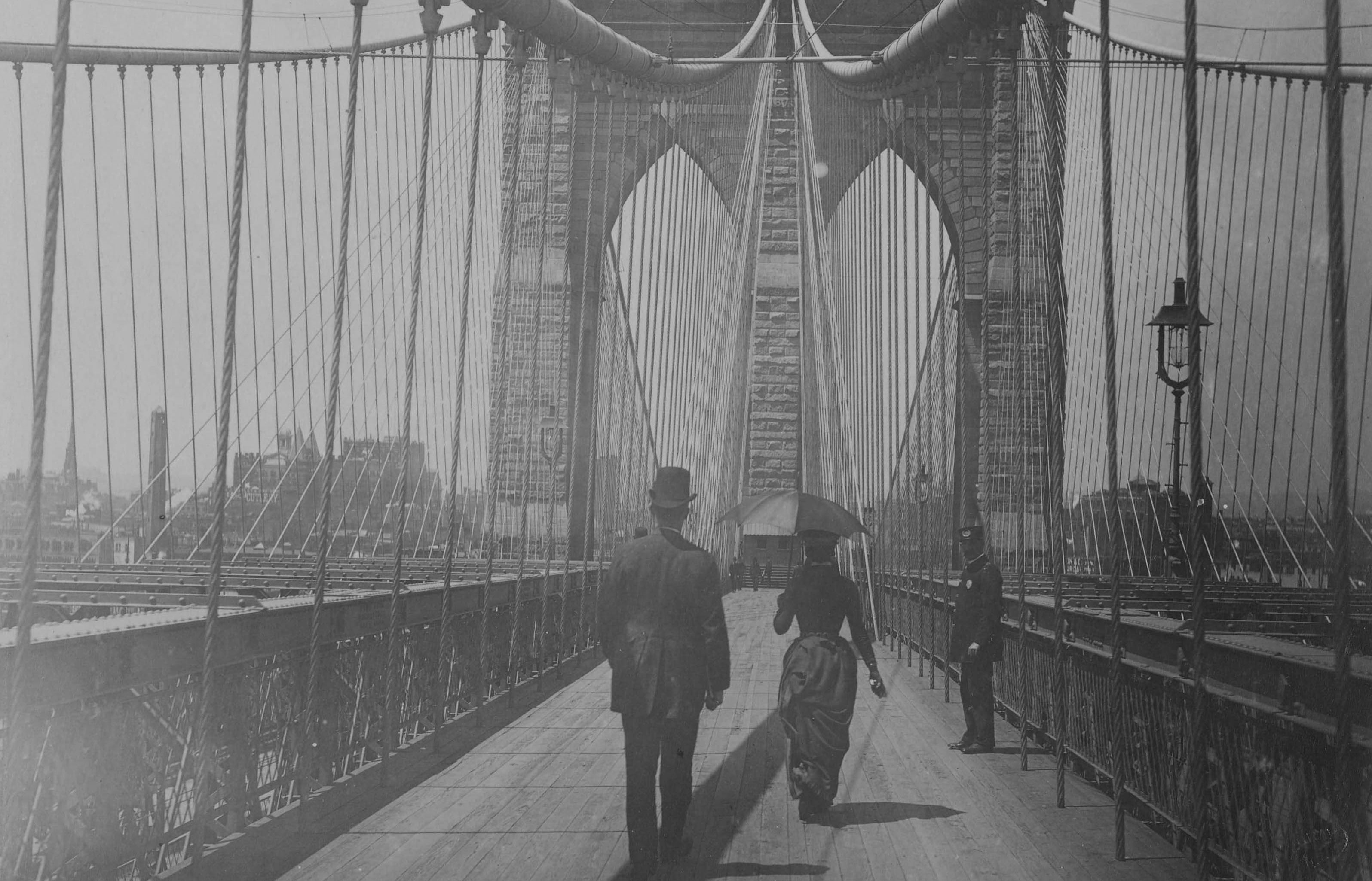 Auf der Brooklyn Bridge. Es sind drei Personen zu erkennen.