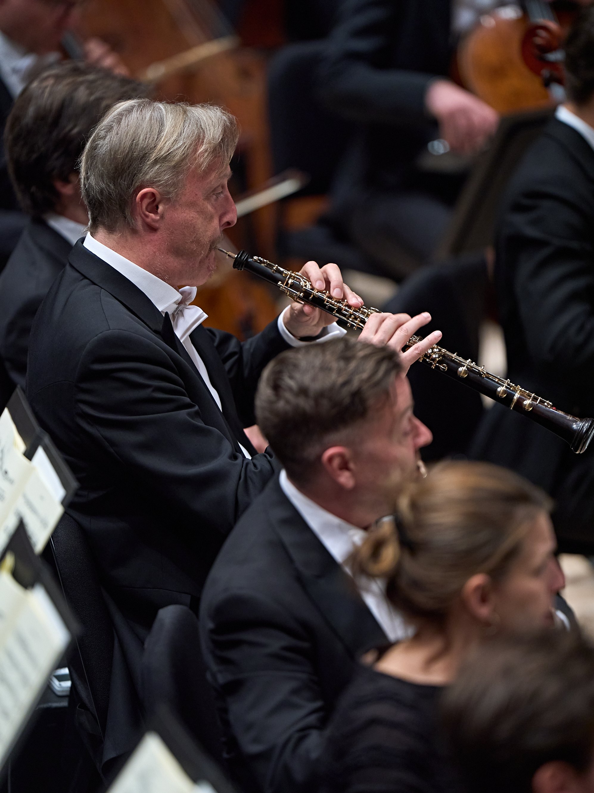 Ein Oboist im Smoking spielt in einem Orchester.