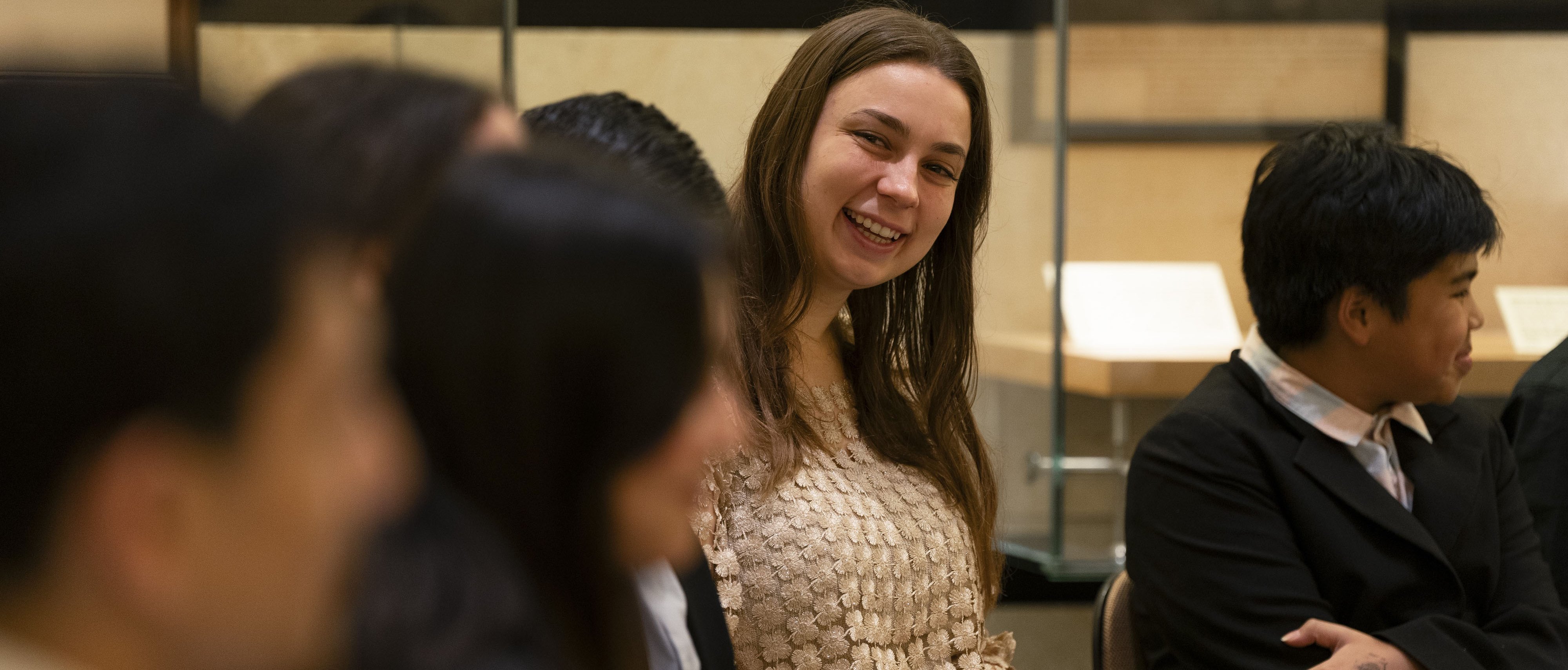 Frau sitzt mit Infoblatt in einer Reihe mit anderen Menschen und lächelt in die KameraKonzerteinführung in der Philharmonie Berlin