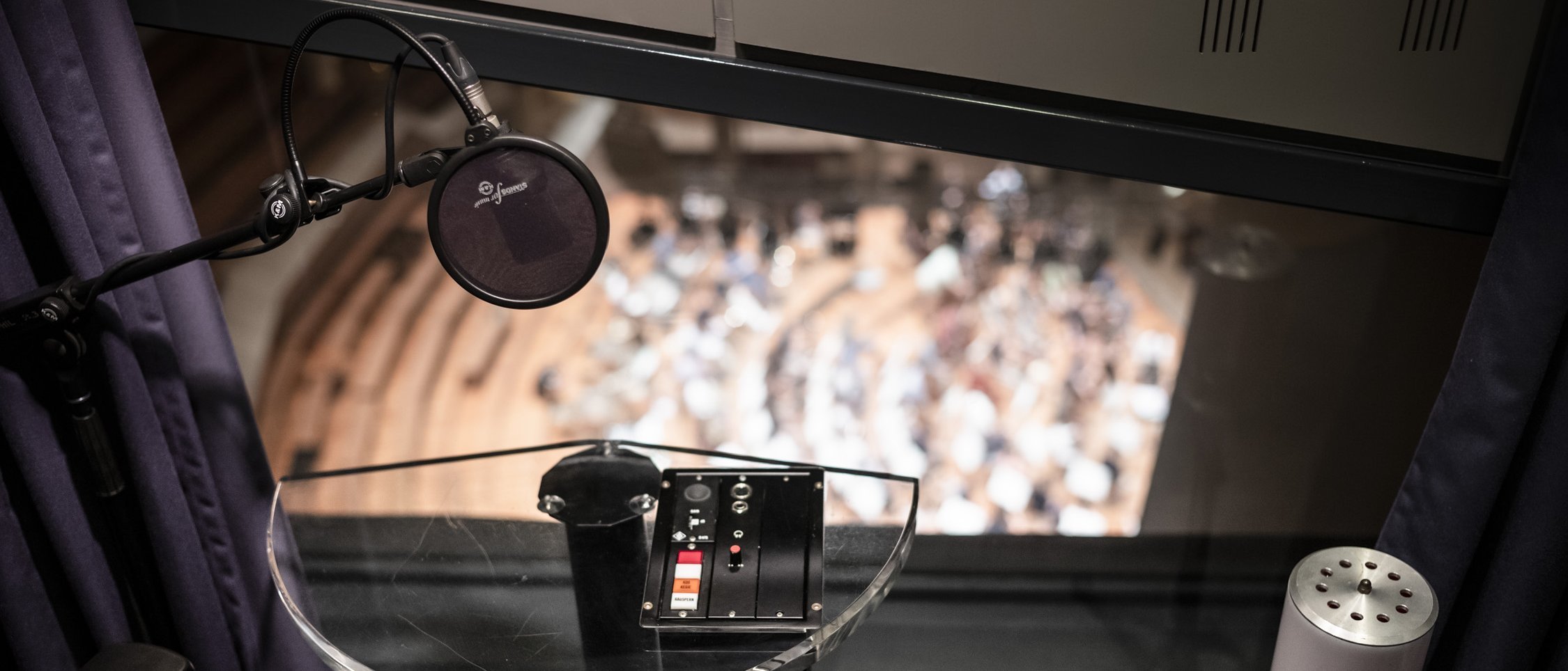 Image from the recording studio looking down on the stage of the Philharmonie Berlin. A mircophone is in the foreground.