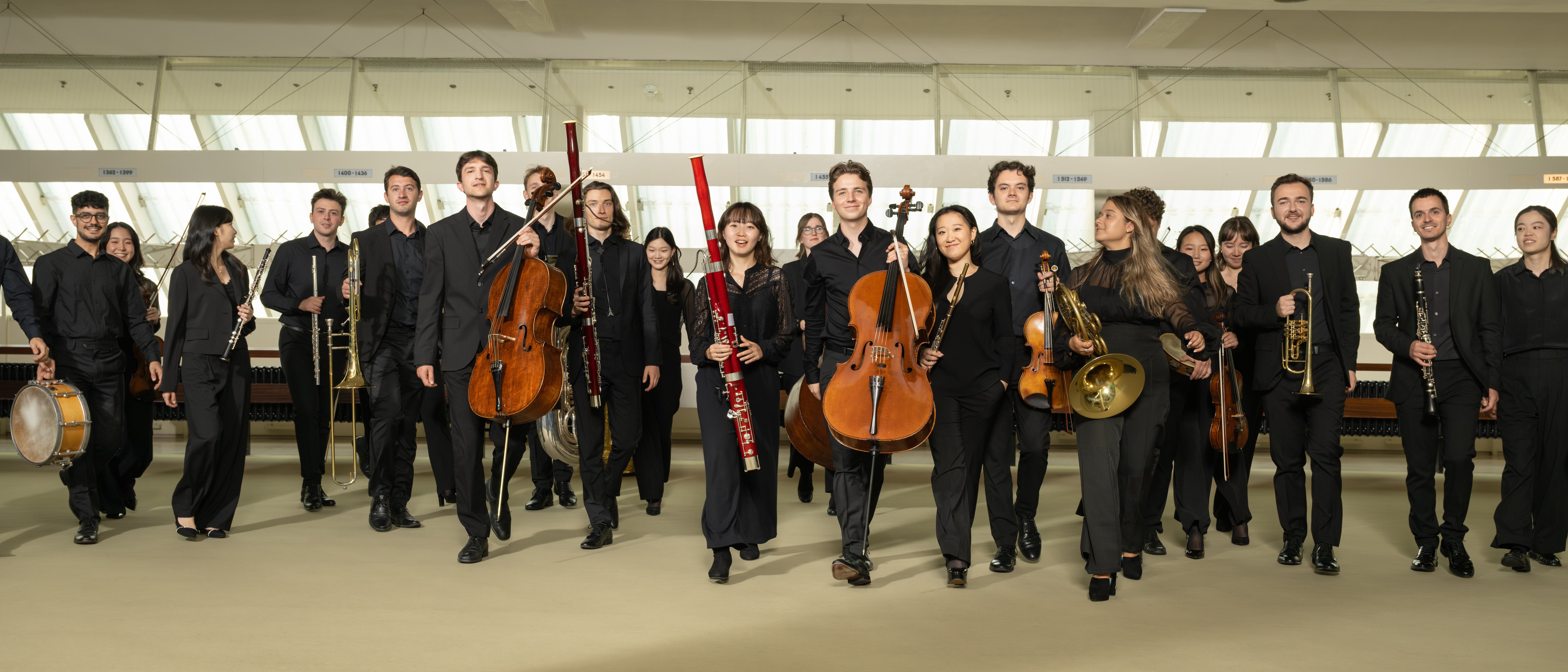 Members of the Karajan-Akademie, dressed in black concert attire, walk towards the camera.