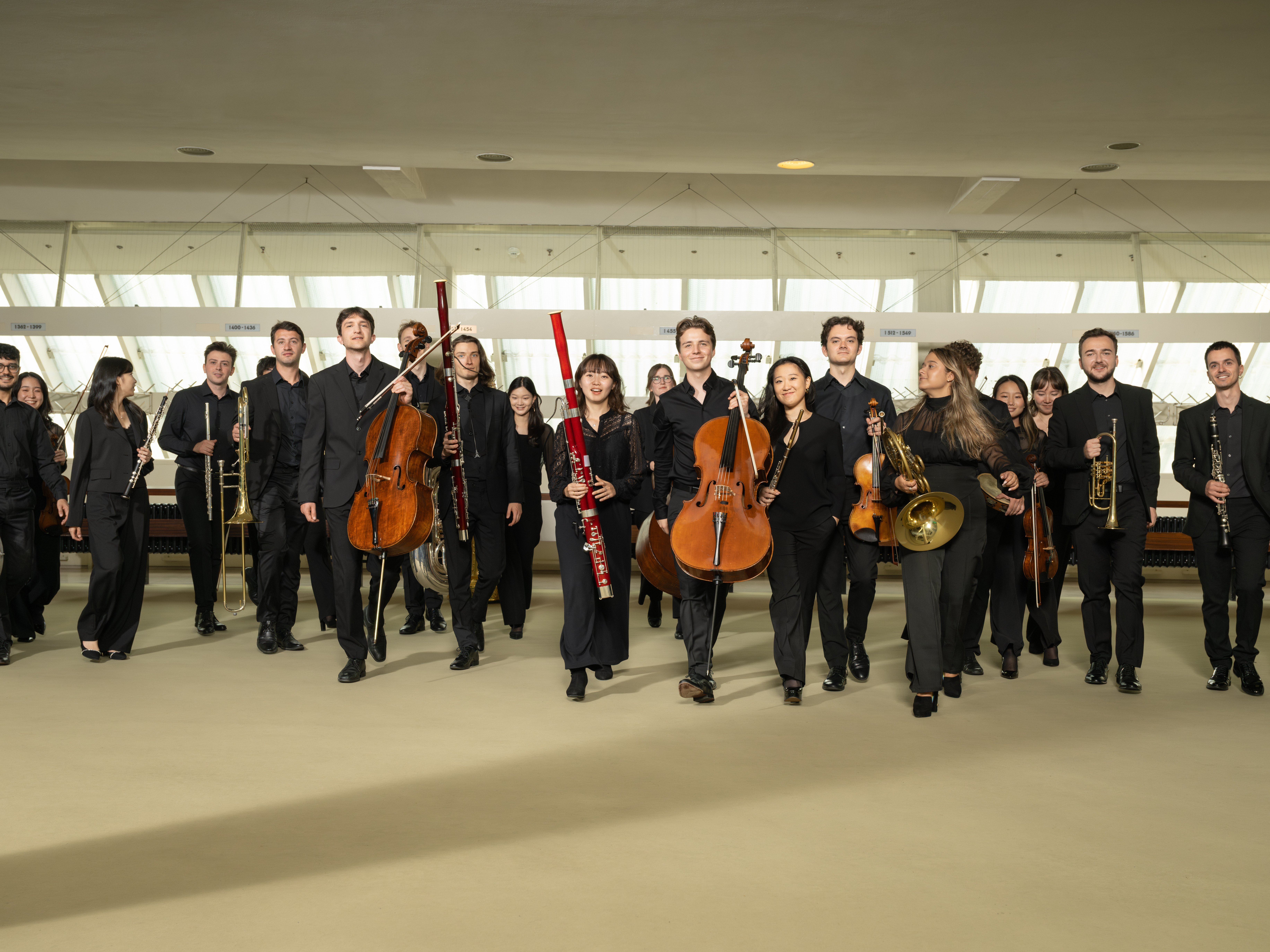 Mitglieder der Karajan-Akademie in schwarzer Konzertkleidung laufen auf die Kamera zu. 