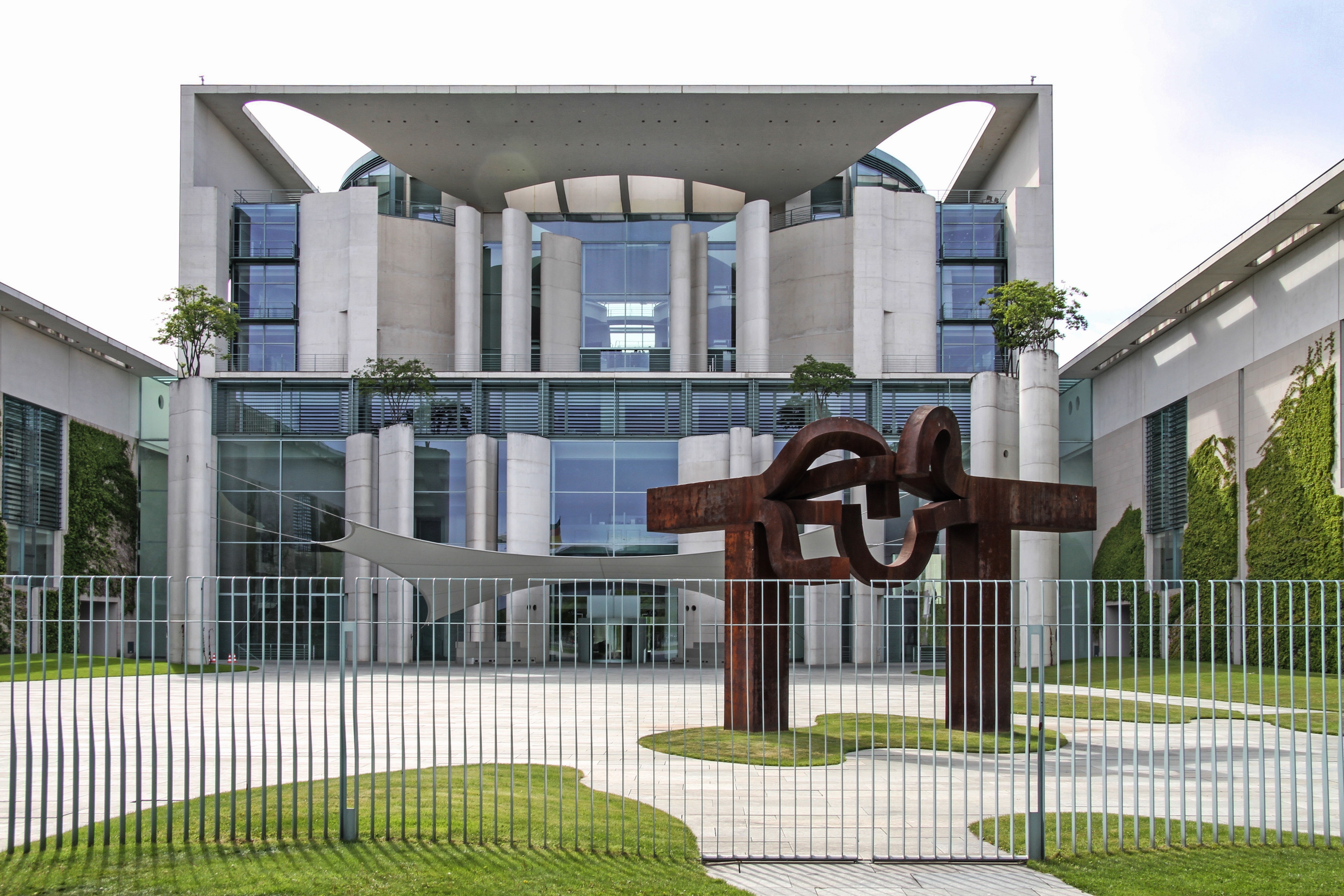 State building with sculpture behind fence