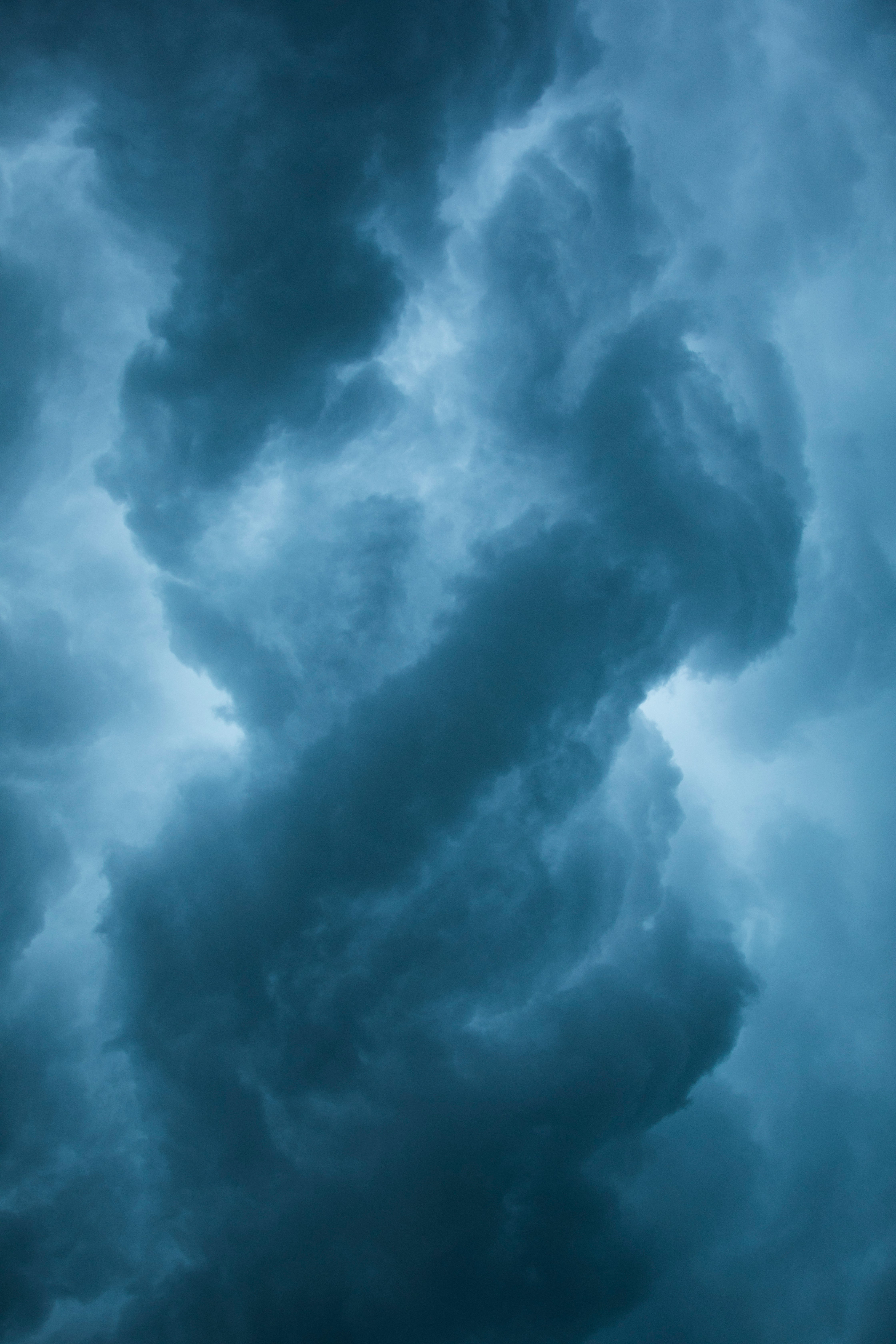 Dark, swirling storm clouds fill the sky, illuminated by a pale blue light, creating a dramatic and ominous atmosphere.