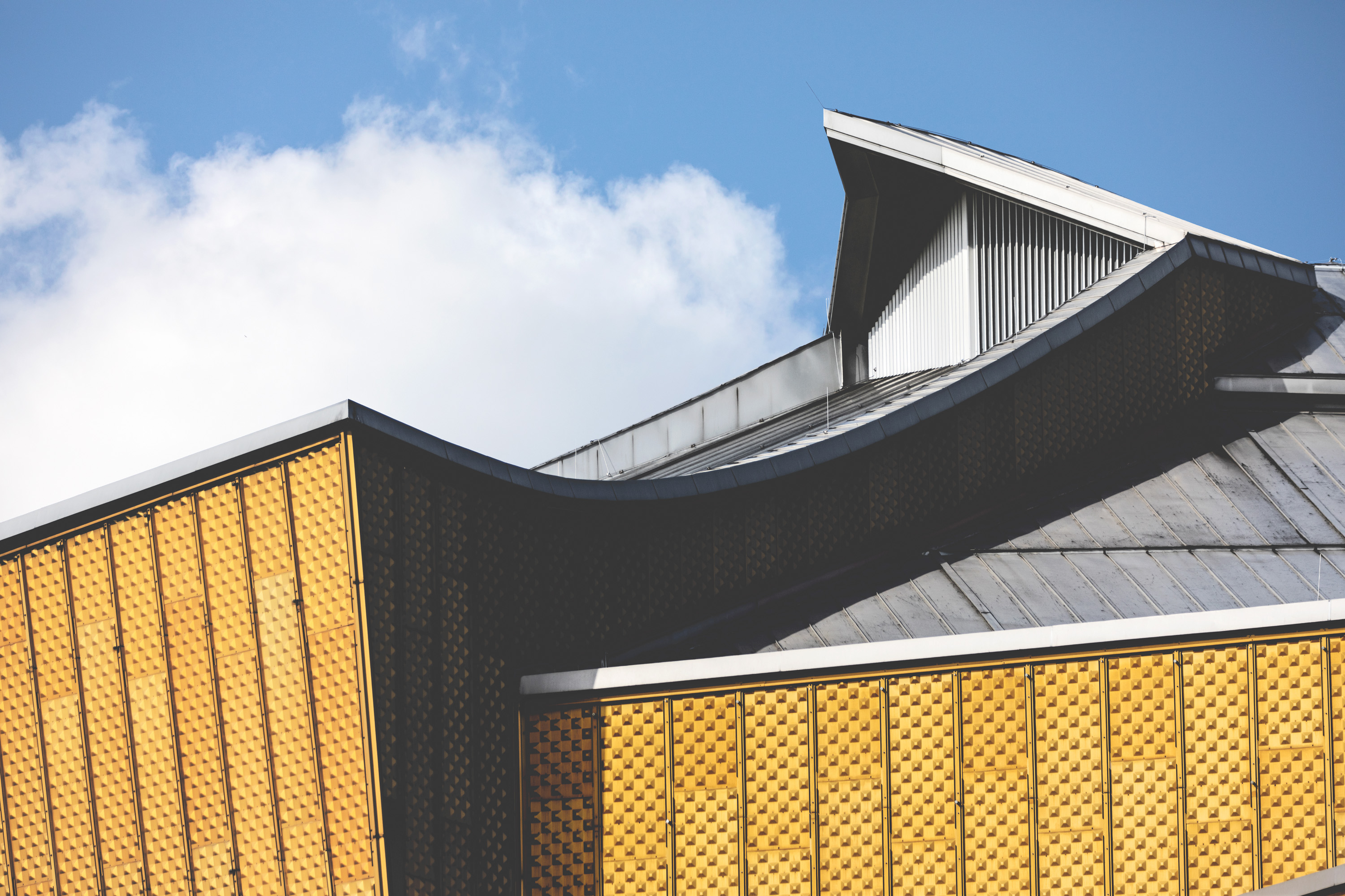 Metal roof of the Philharmonie, the façade glows yellow-gold.