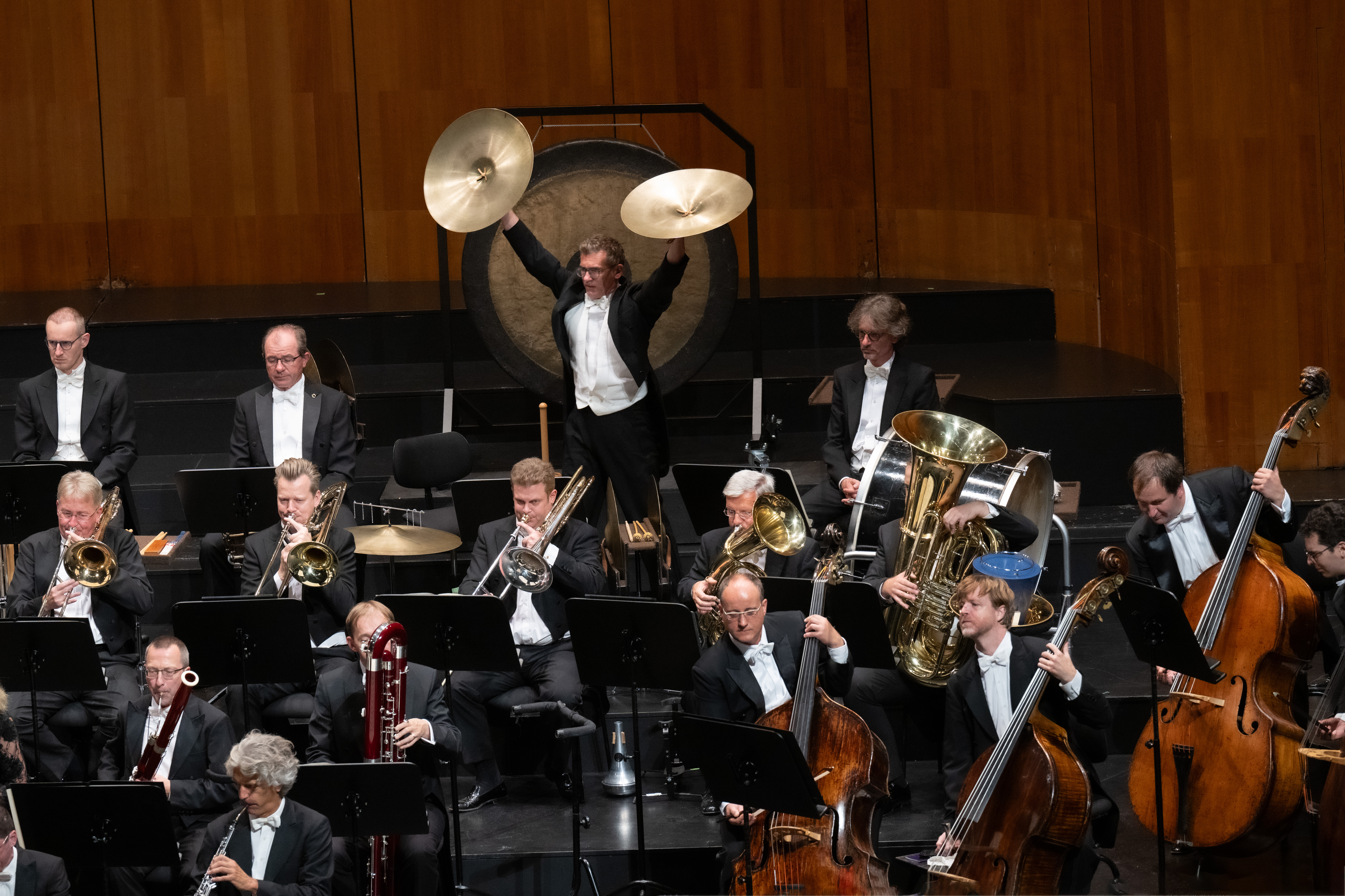 Musician plays the cymbals, other orchestra members around