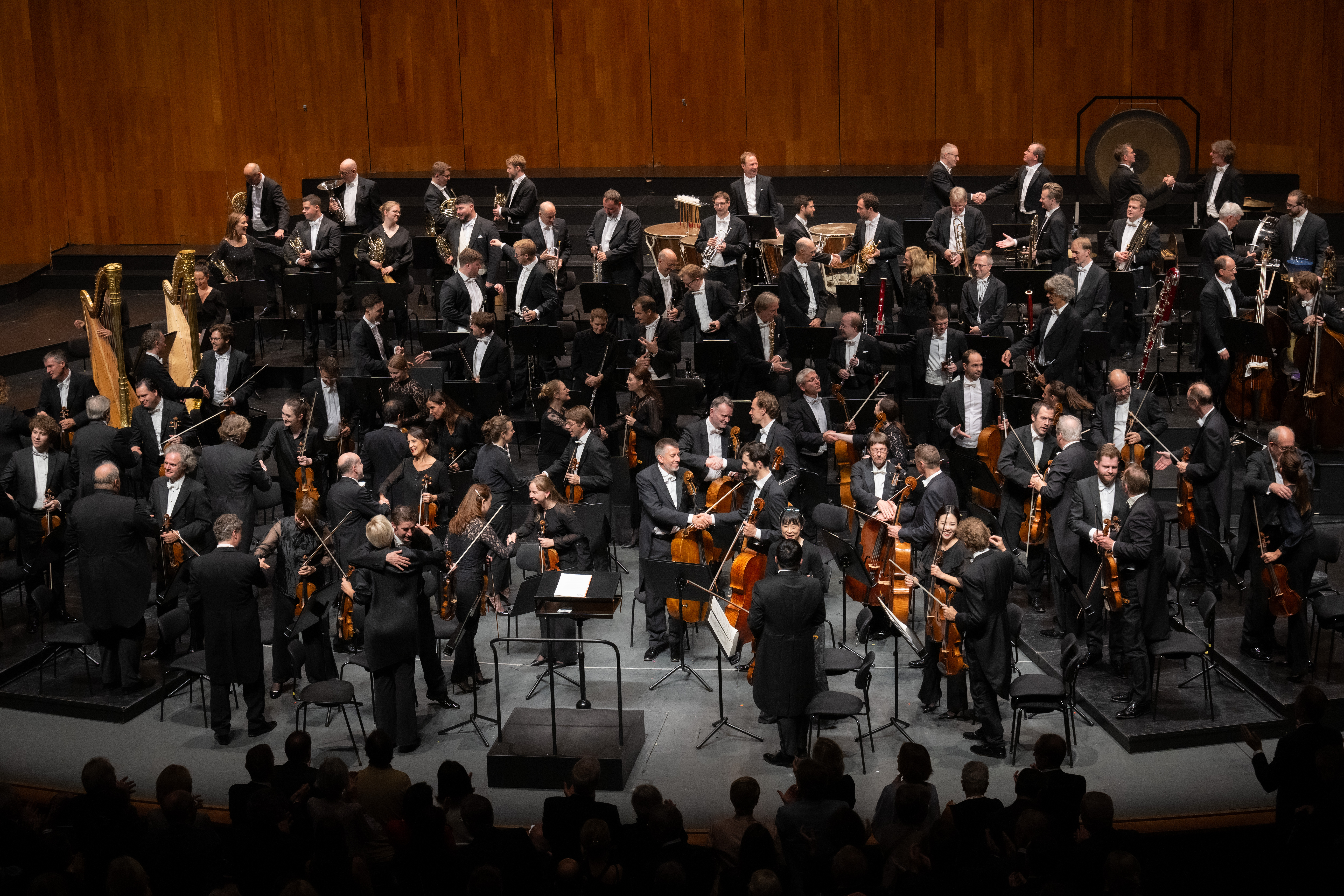 Orchestra members hugging and giving eachother a hand after the performance
