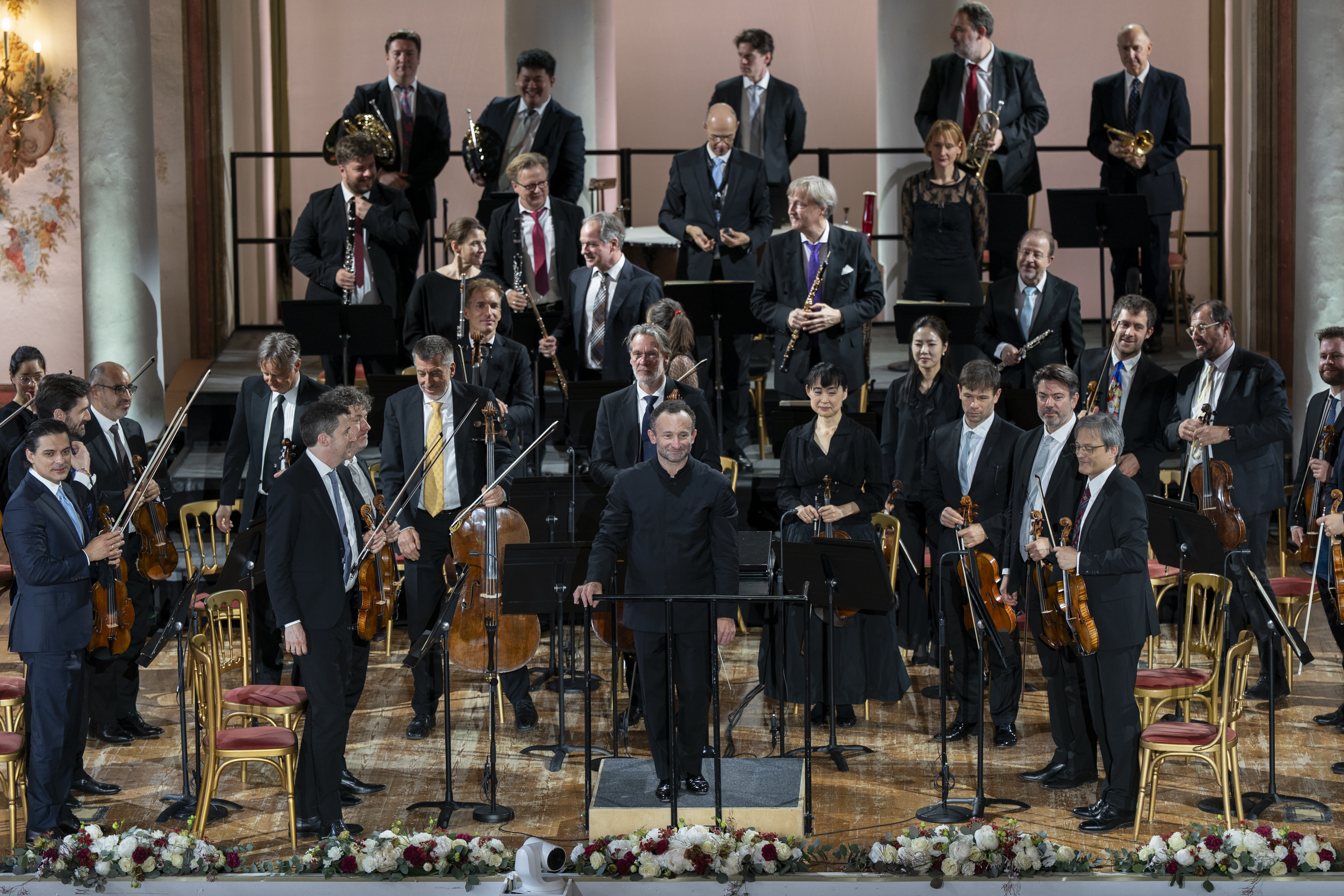 Chefdirigent Kirill Petrenko verbeugt sich nach dem Konzert auf der Bühne. Hinter ihm steht das Orchester.