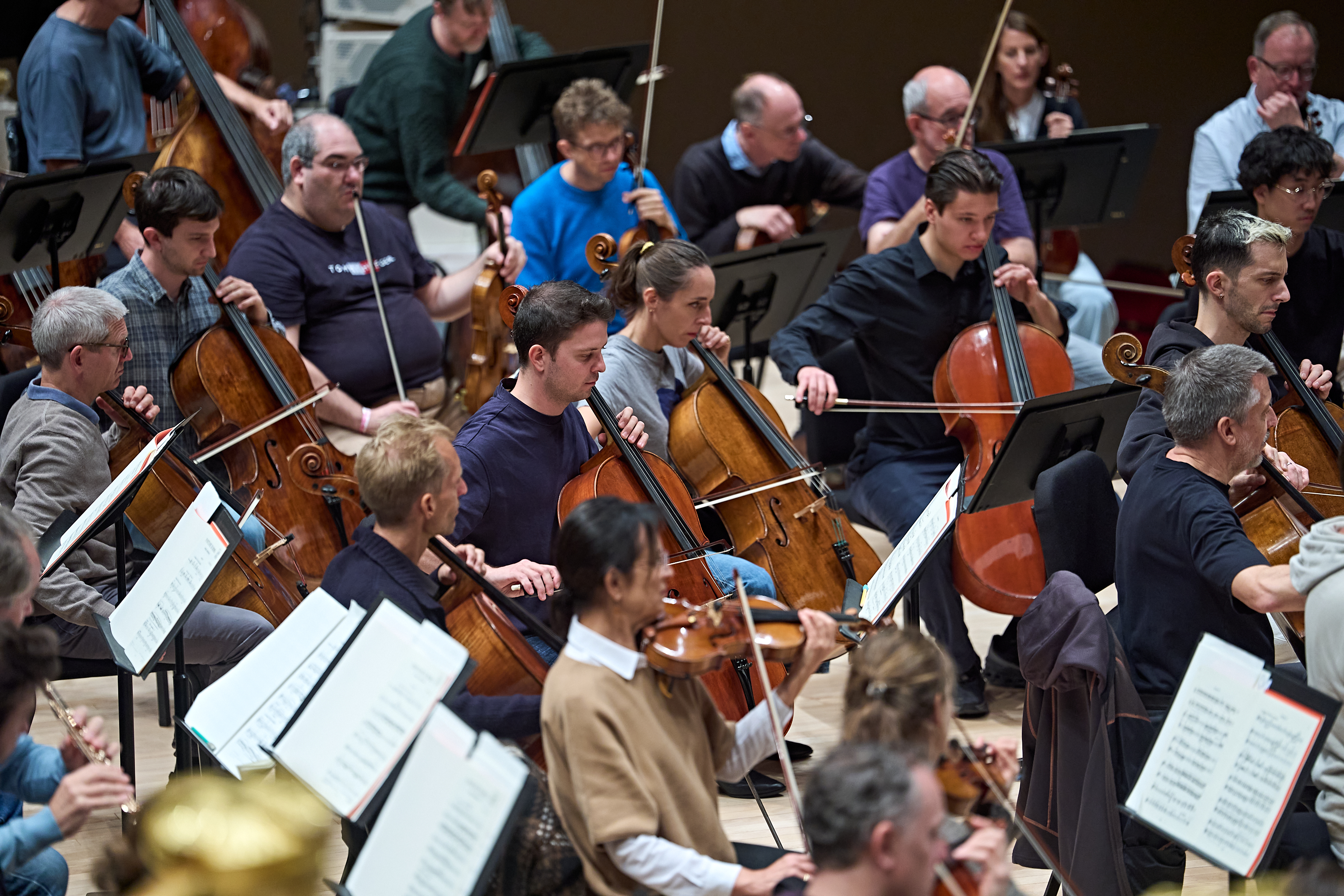 Ein Orchester aus Musikern, die Cello und Geige spielen, während sie von Notenständern Noten ablesen.