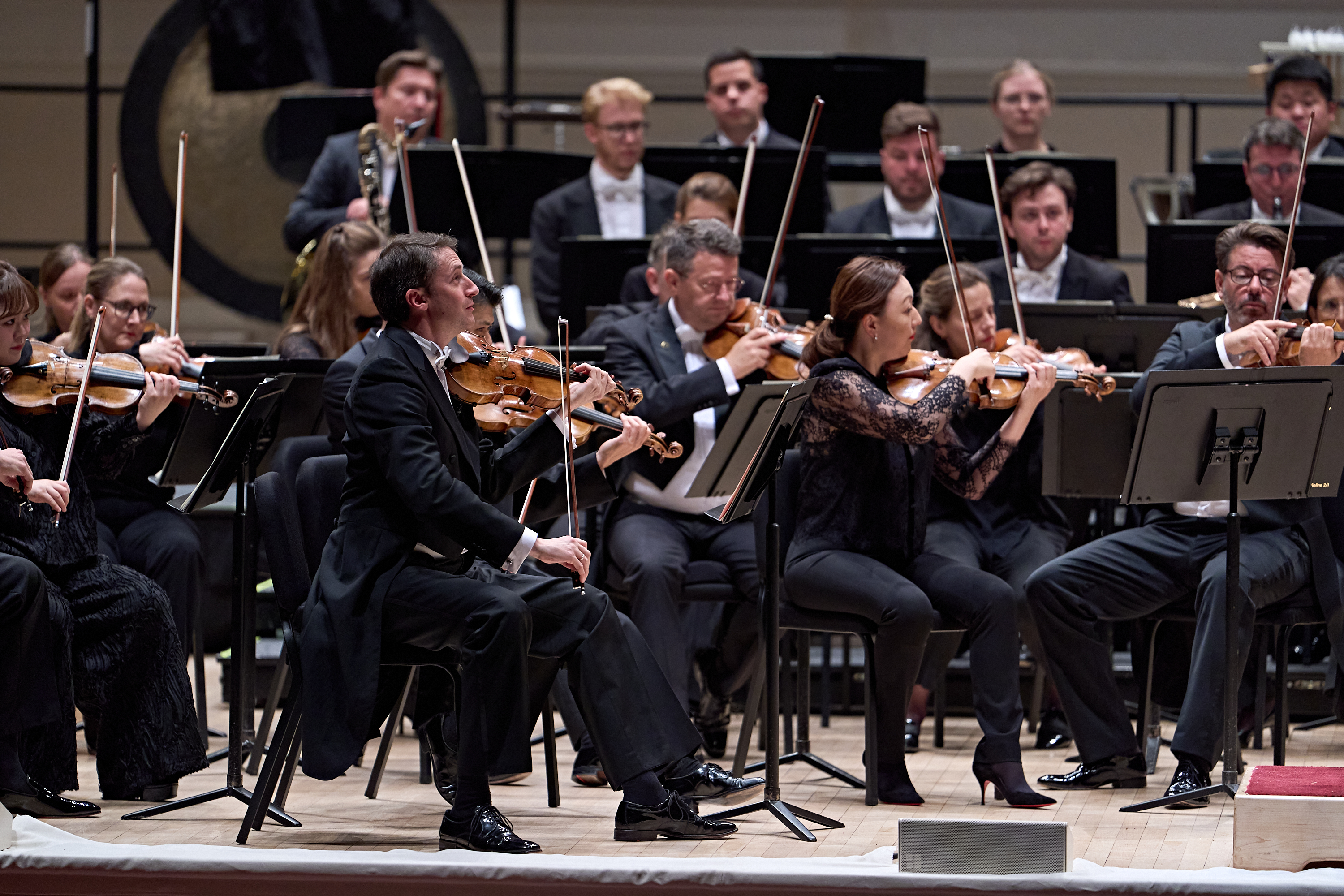 Orchestermusiker, die während einer Aufführung auf einer Bühne Geige spielen.