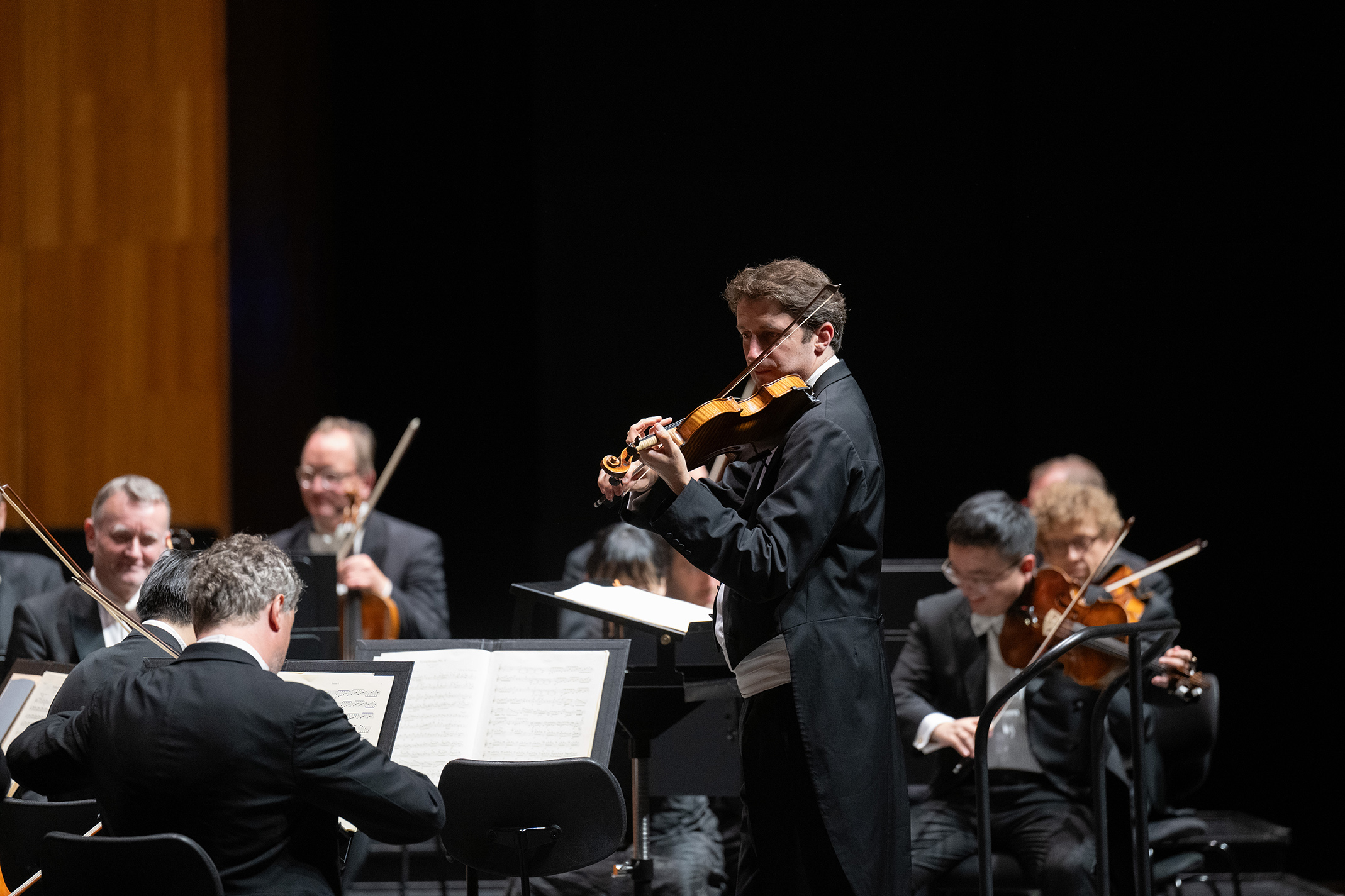 Male violinist among the orchestra tuning together