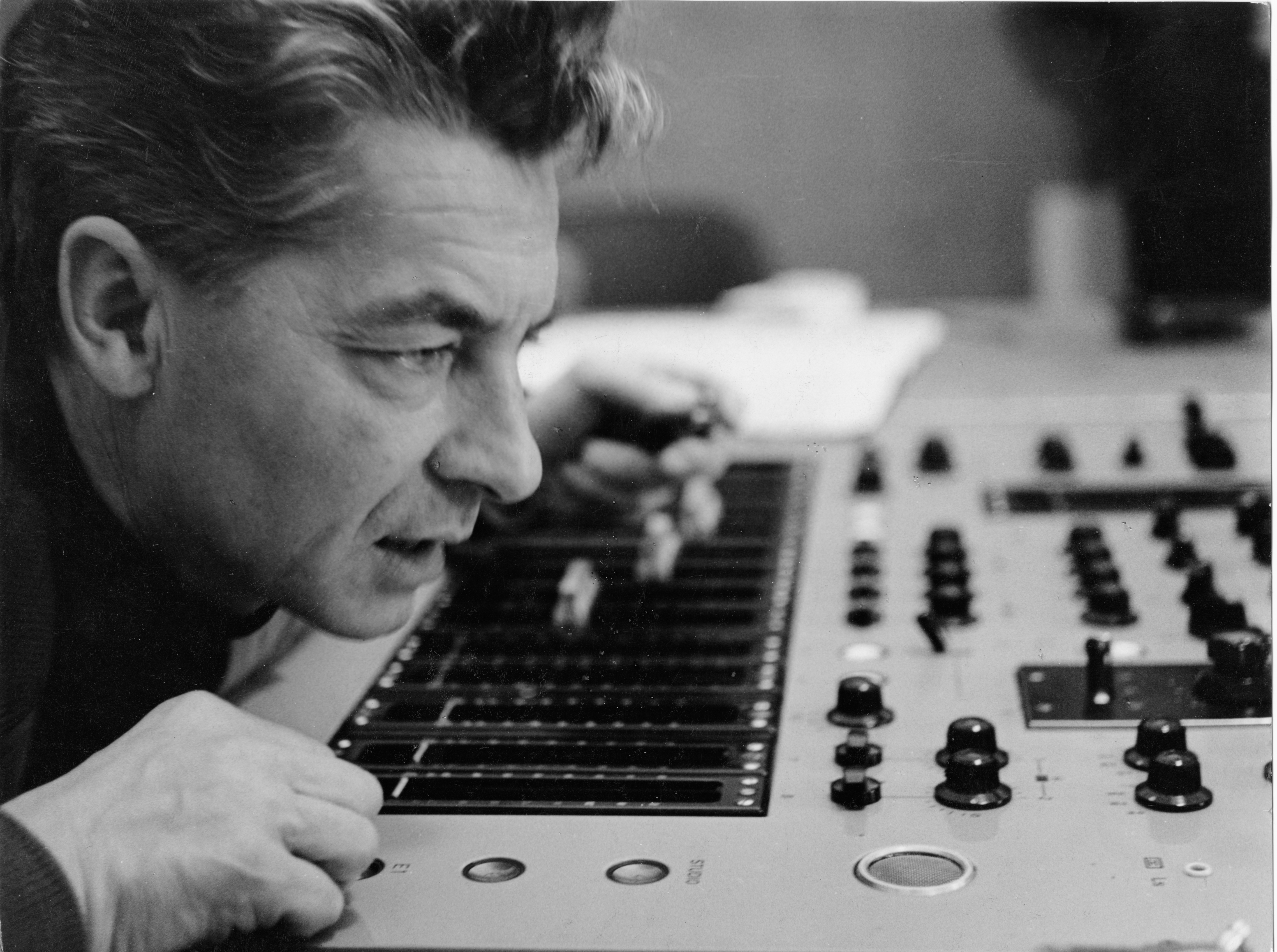Herbert von Karajan über einem Mischpult gebeugt.