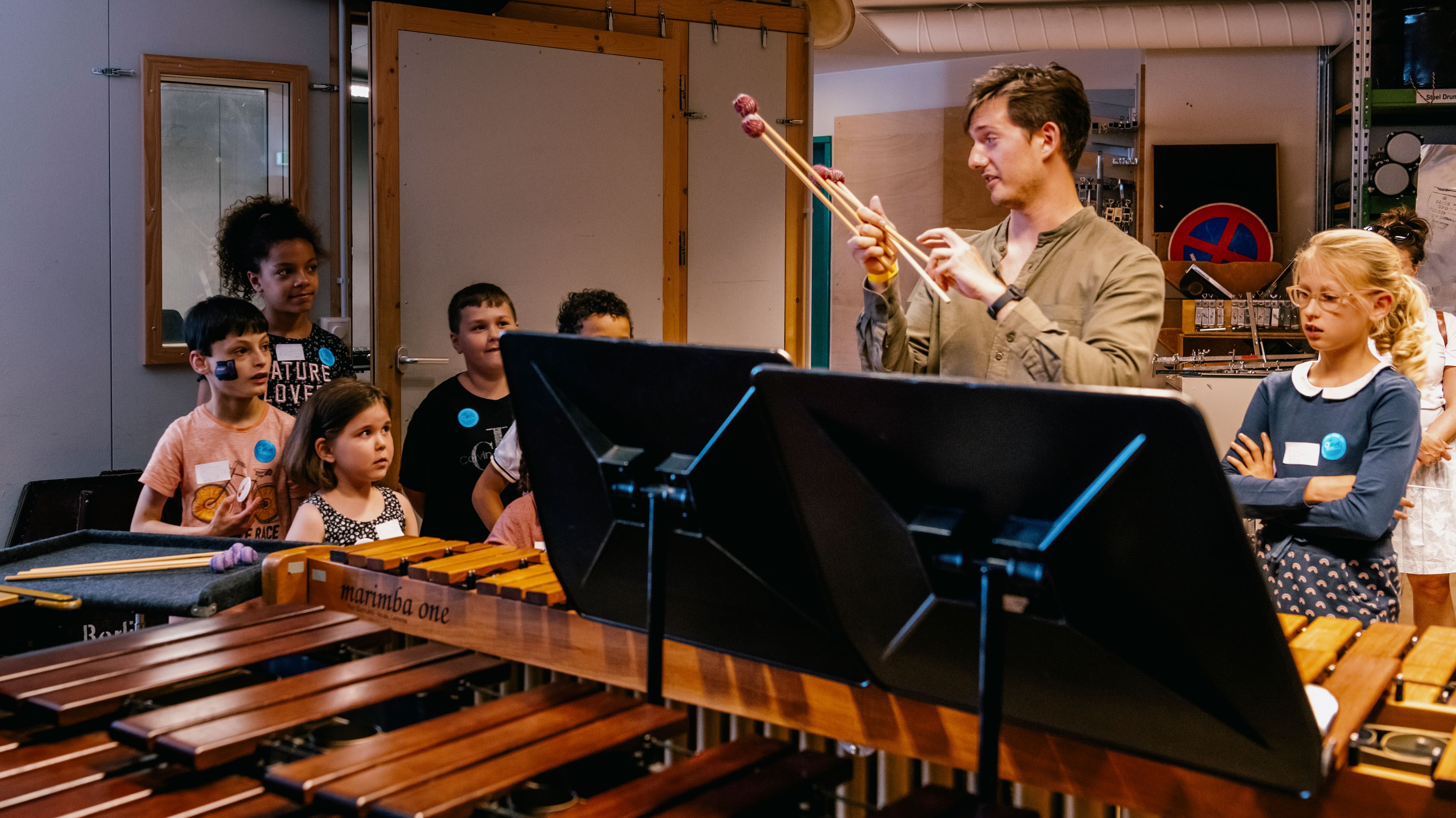 Schlagzeuger zeigt Kinder ein Marimbaphon und verschiedene Schlegel