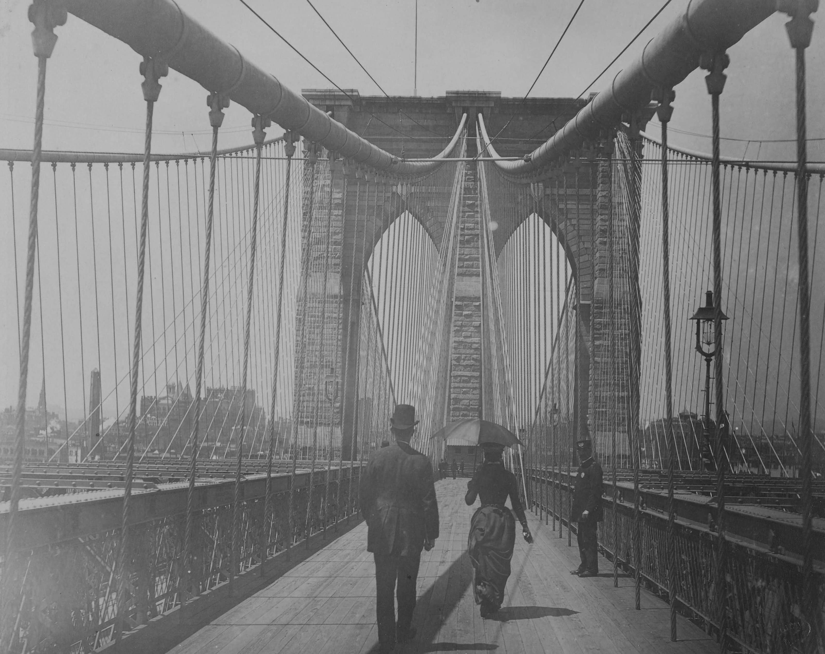 Auf der Brooklyn Bridge. Es sind drei Personen zu erkennen.