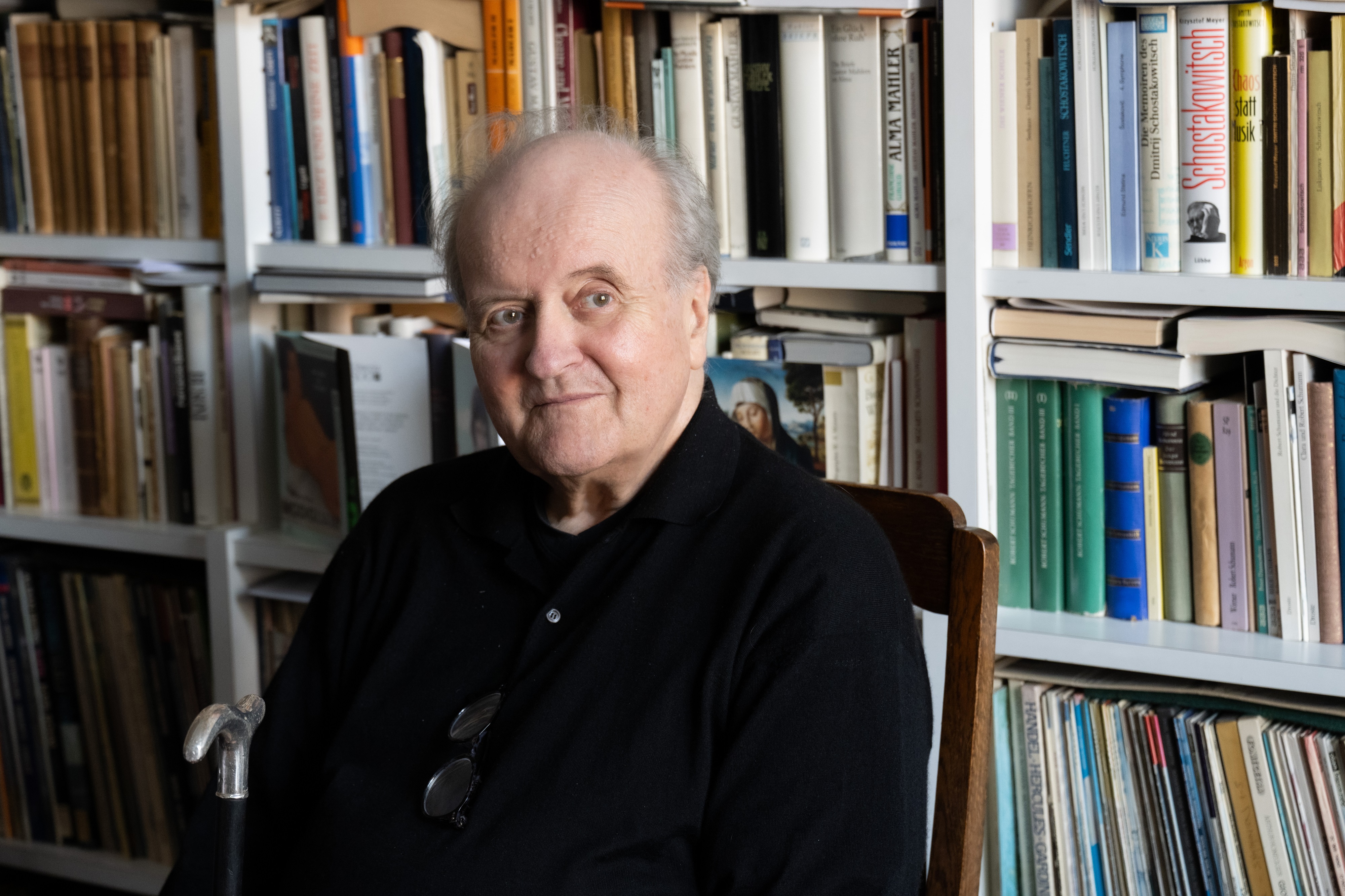 Wolfgang Rihm sits at home in front of his bookshelf