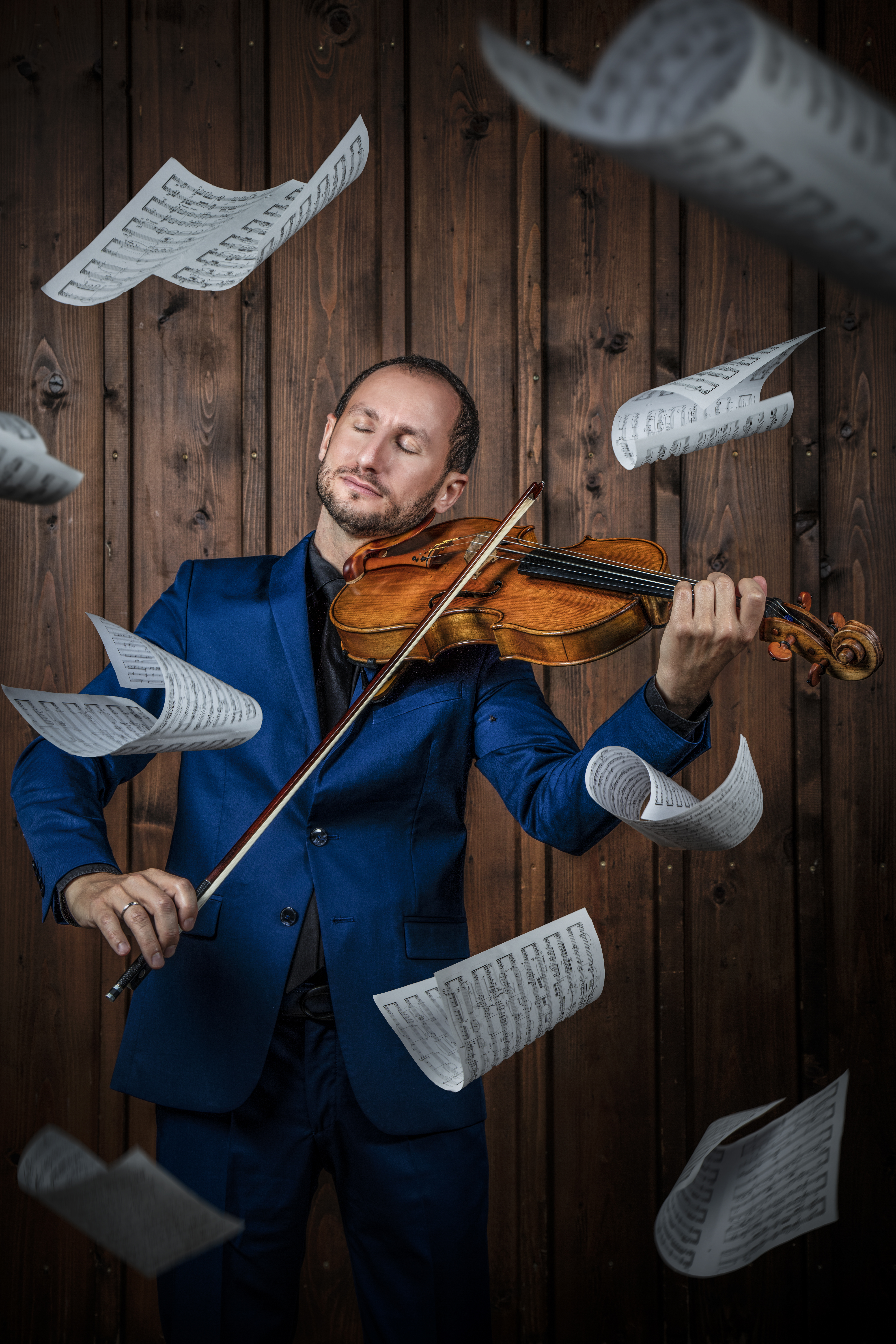 Bratscher Antoine Tamestit mit seinem Instrument in den Händen. Notenblätter fliegen um ihn herum.