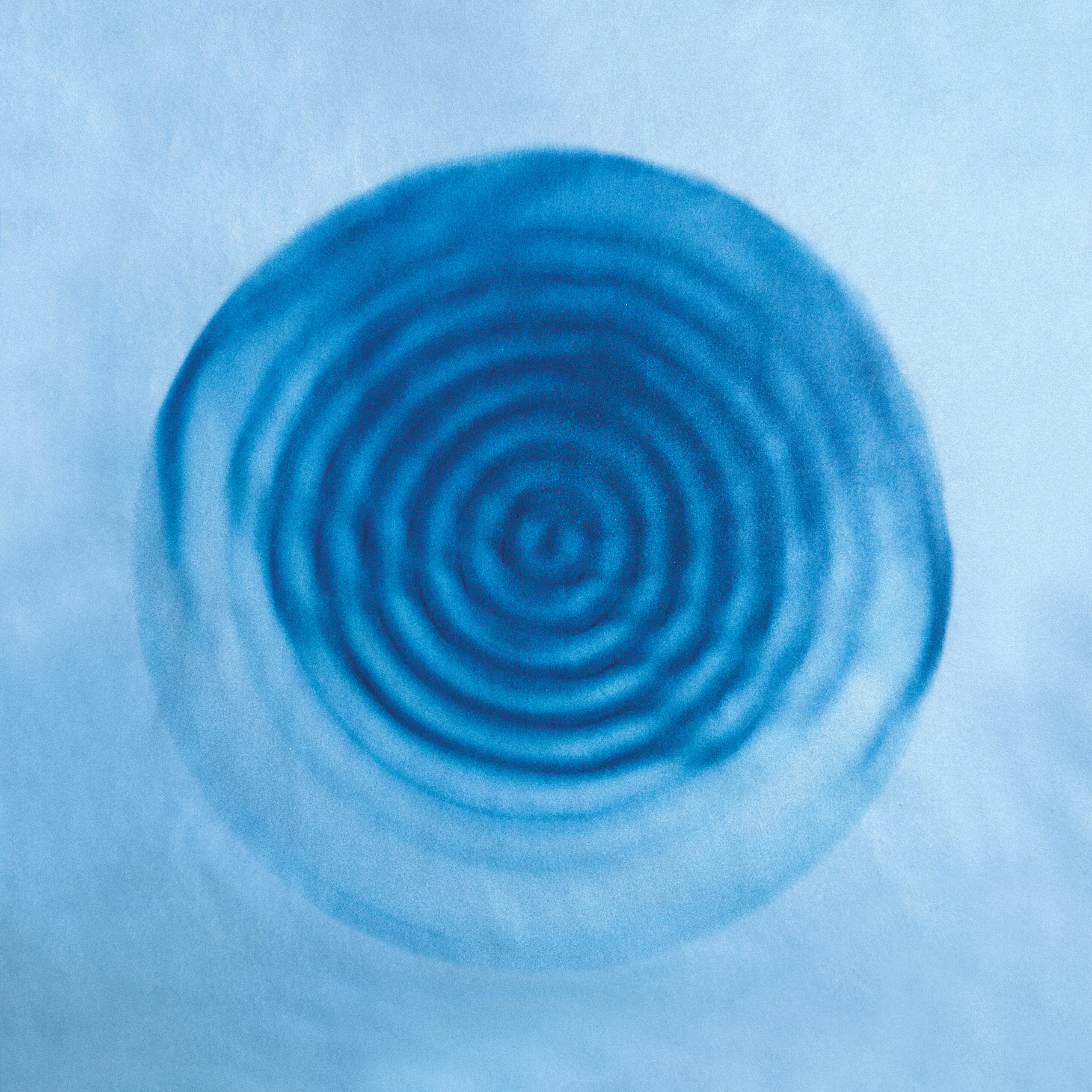 Ein blaues, kreisförmiges Muster mit konzentrischen Ringen strahlt auf einem hellblauen Hintergrund nach außen und erinnert an Wellen im Wasser oder an die Visualisierung einer Schallwelle.